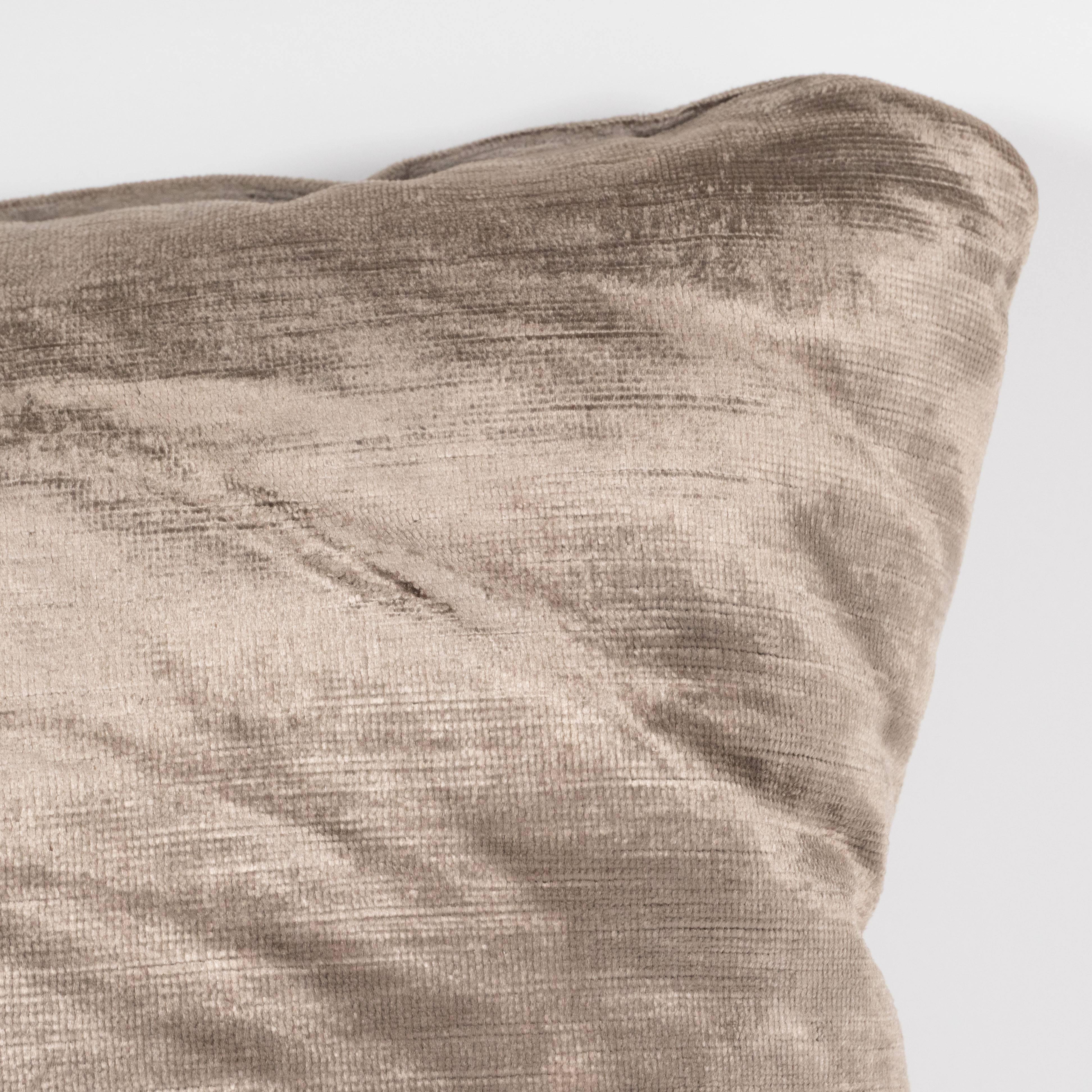 This gorgeous pillow, realized in a rich smoked taupe hue, features the gentle luster characteristic of the finest velvet. Its color tone reads as both neutral, suggesting antiqued pewter and organic. Its simple form and versatile shade- matching
