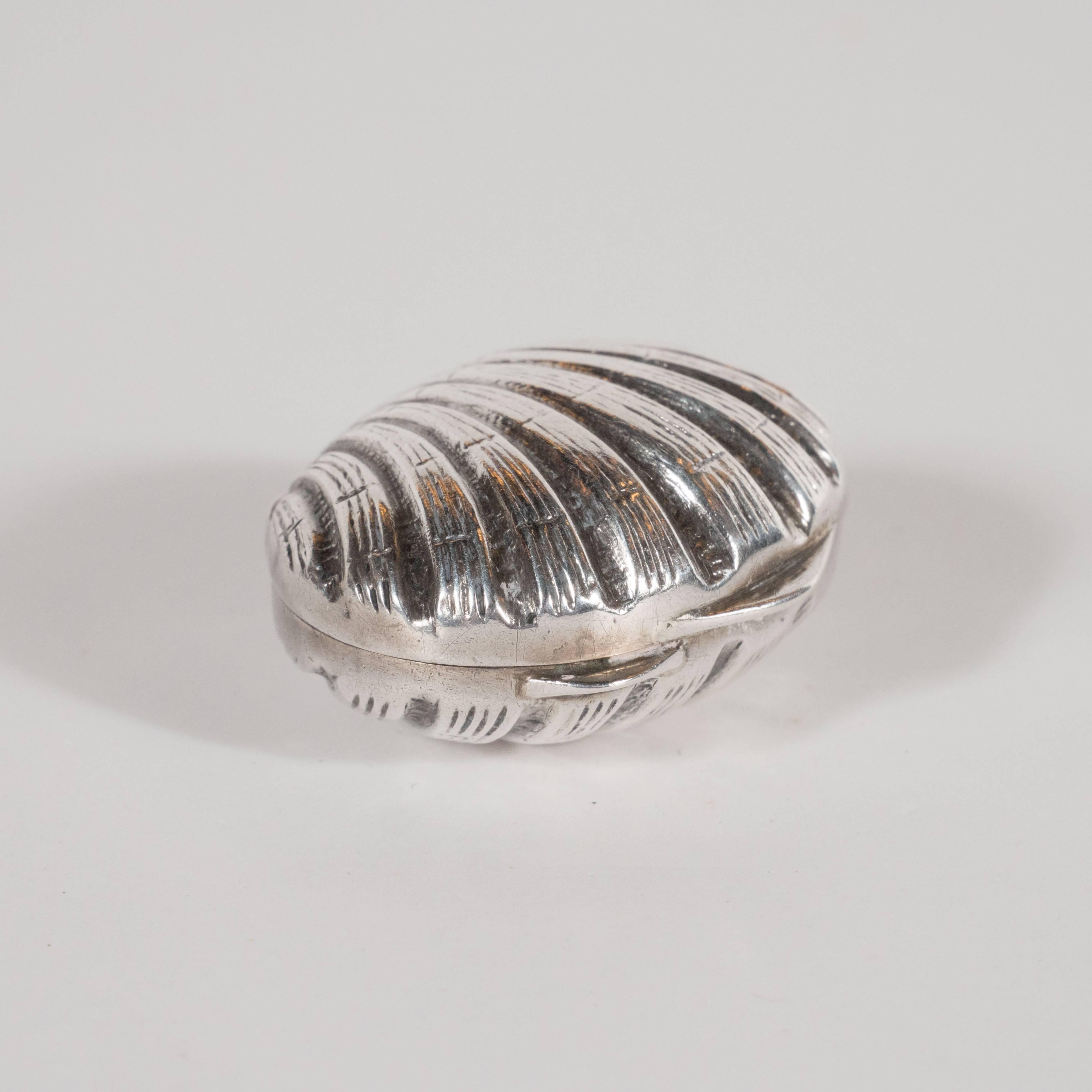 This lovely sterling silver pill case, fabricated in the form of a scallop shell, was realized by Tiffany & Co.- the most storied and celebrated name in American silver- circa 1960. It features finely reeded curvilinear lines extending out from the