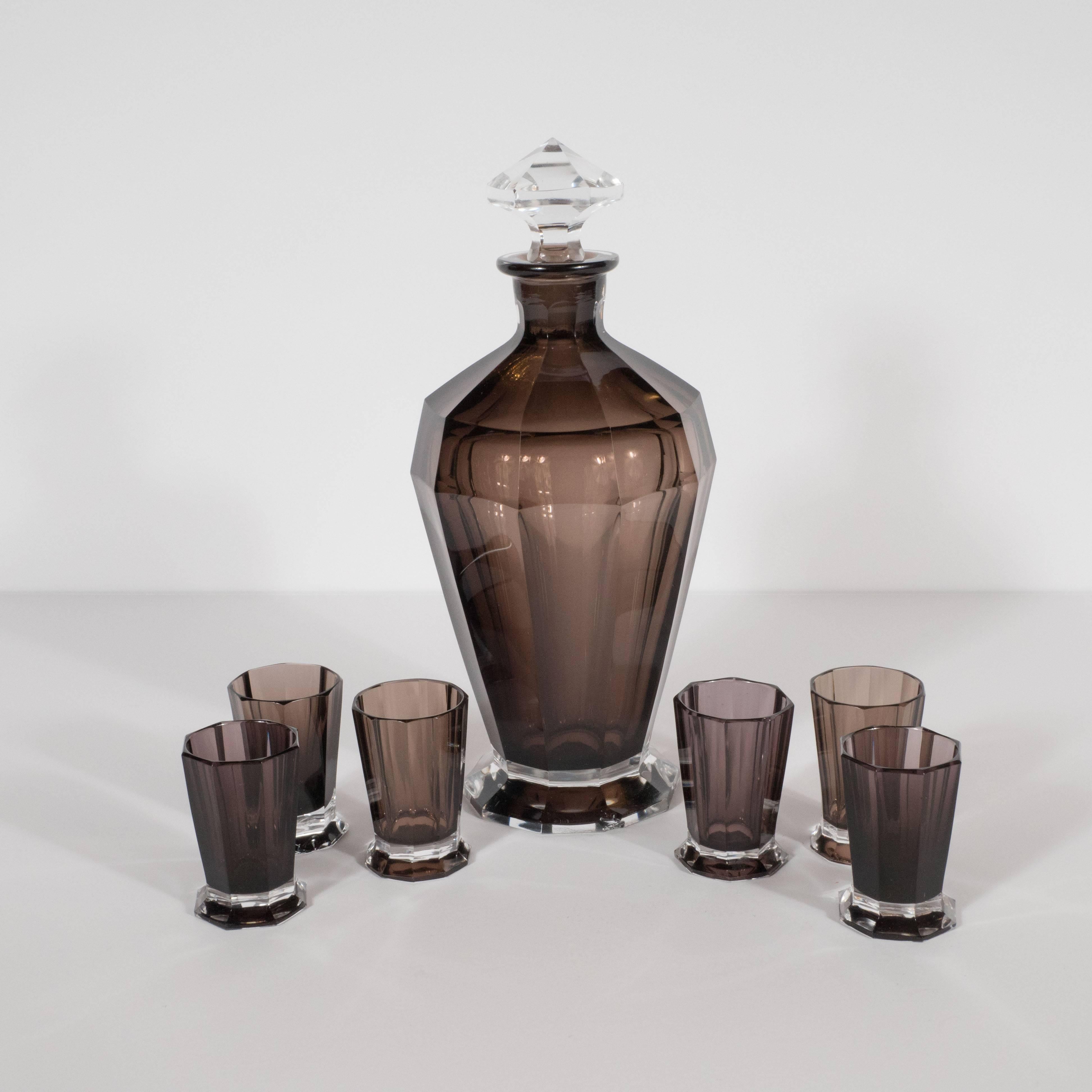 This elegant Art Deco bar set includes six shot octagonally cut and conically shaped decanter and six shot glasses that also have eight bevel cut sides. The base of each glass, as well as the decanter, has been created from clear glass, creating a