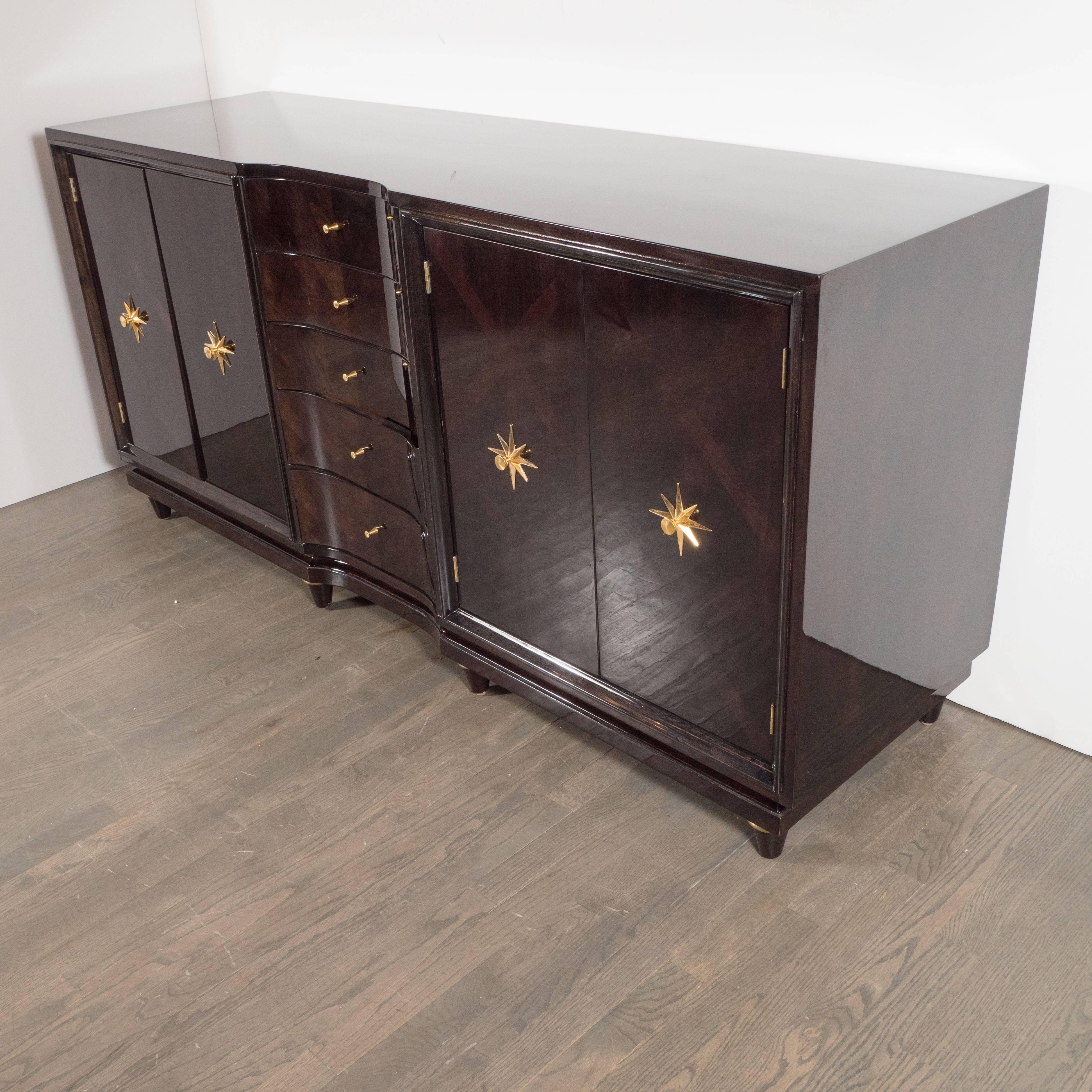 This fine ebonized walnut sideboard was realized in the United States by the esteemed J.B. Van Sciver Company, circa 1950. There are five center drawers (measuring 15.25" W X 13.75" D each) with hourglass shaped brass pulls culminating in