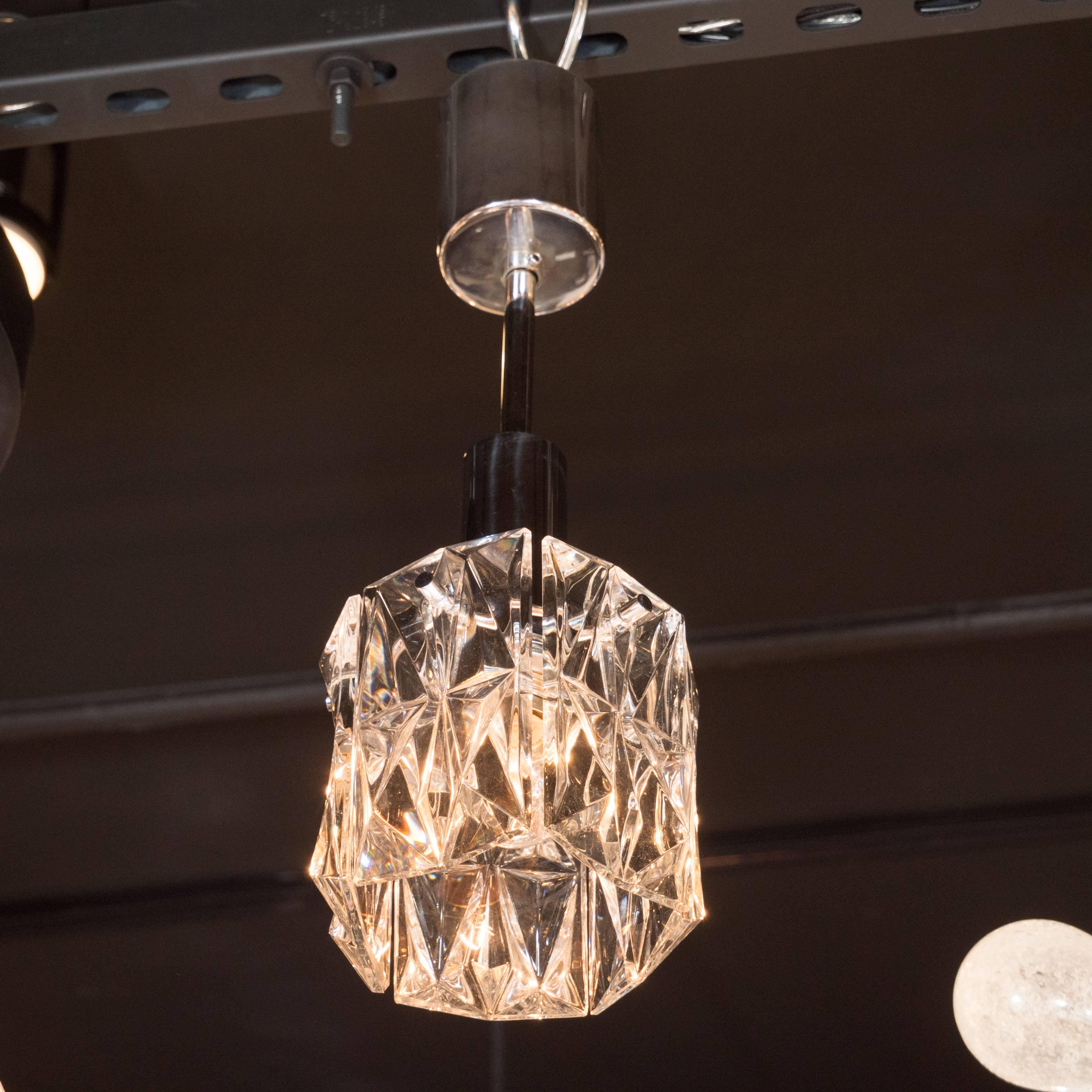 This sophisticated Mid-Century Modern pendant features a single glass shade replete with an abundance of raised geometric patterns etched into its surface, refracting light like a perfectly cut diamond. Produced in Austria by the esteemed producer