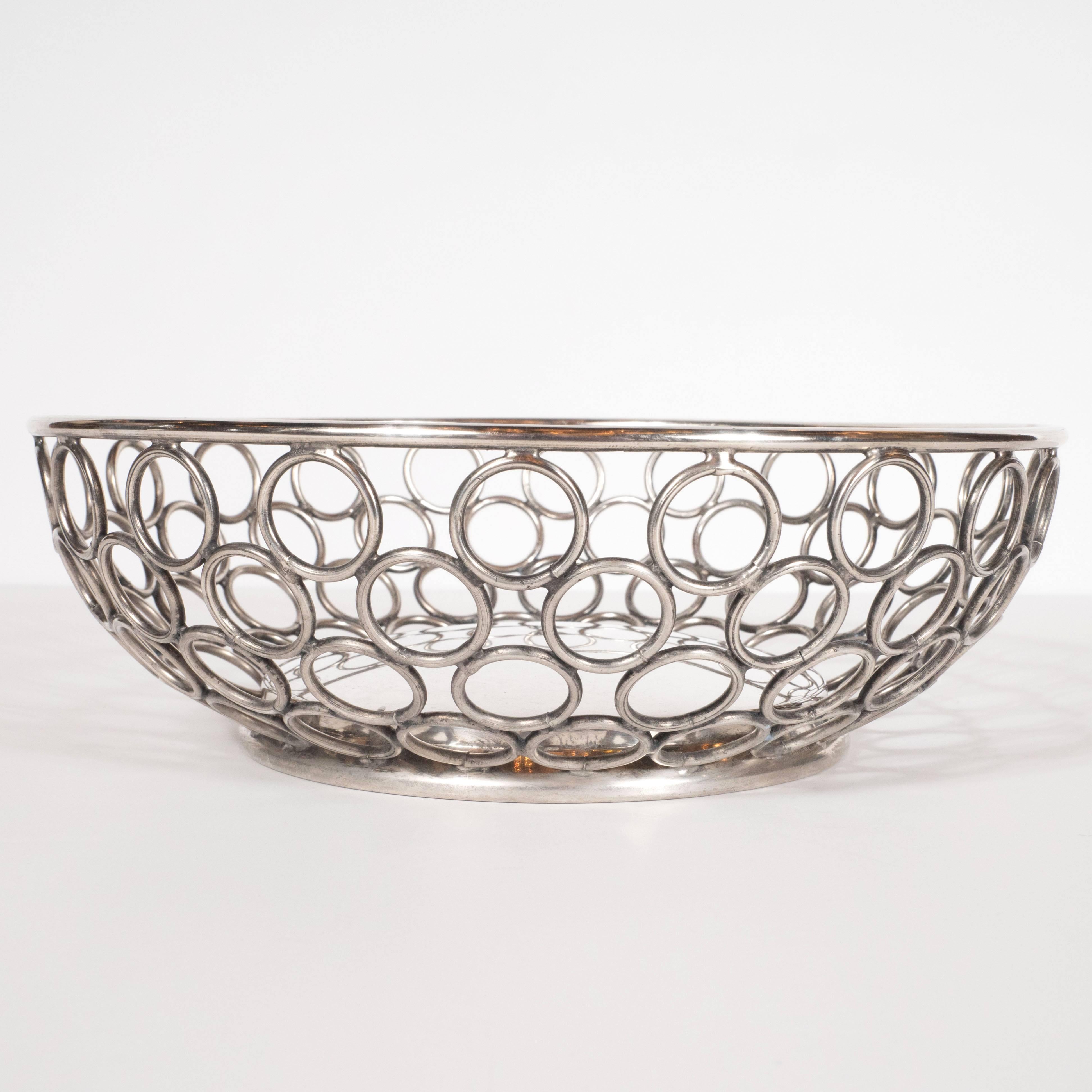 This Mid-Century Modern silver plate bowl or basket was realized in the United States by the renowned Massachussettes based silversmiths, Raimond. This piece reads as quintessentially of the period with its myriad curvilinear forms, including the