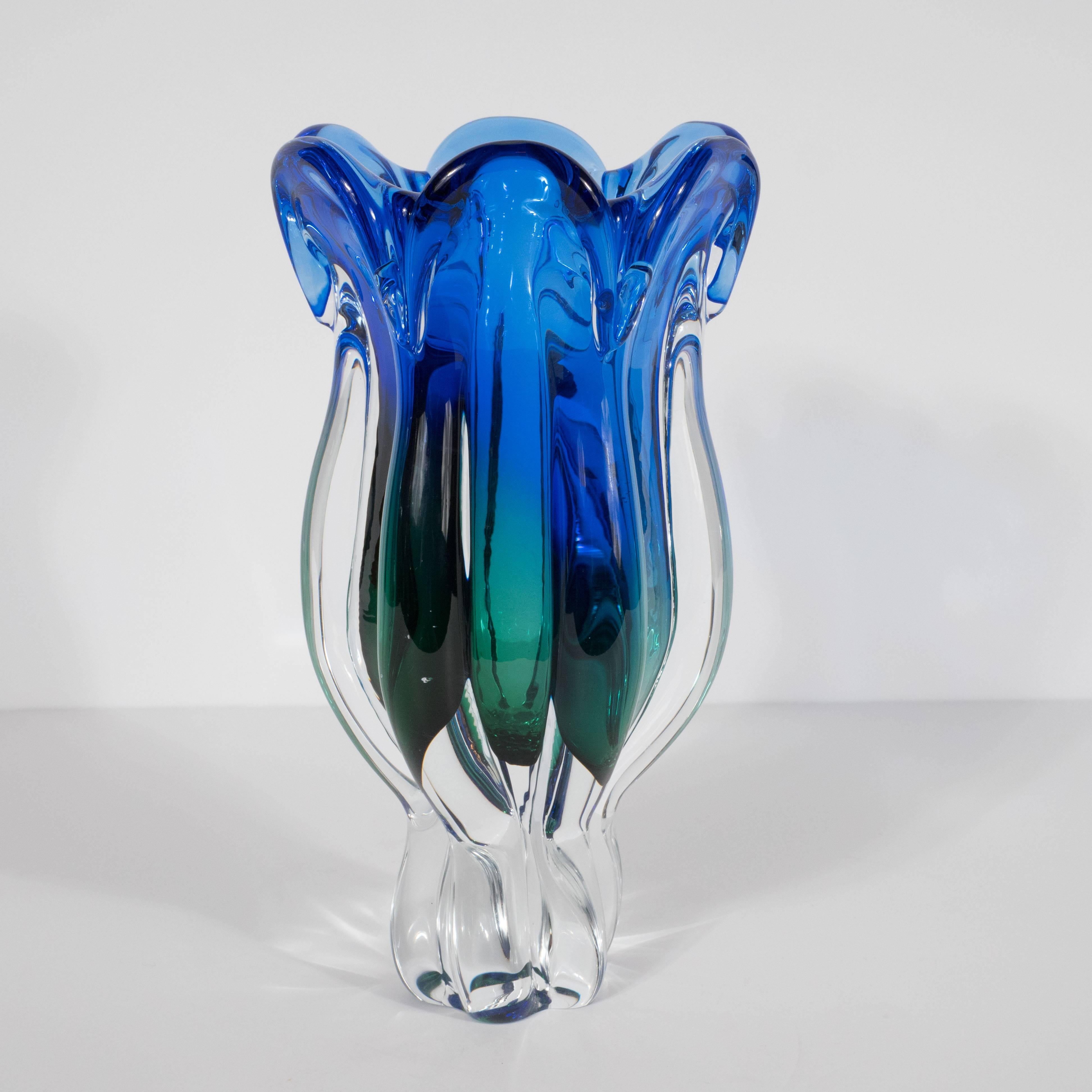 This exquisite Mid-Century Modern vase was realized in Murano, Italy, the Venetian islands renowned for their superlative quality glass production for centuries. It features a translucent glass base with raised and rounded seams undulating along the