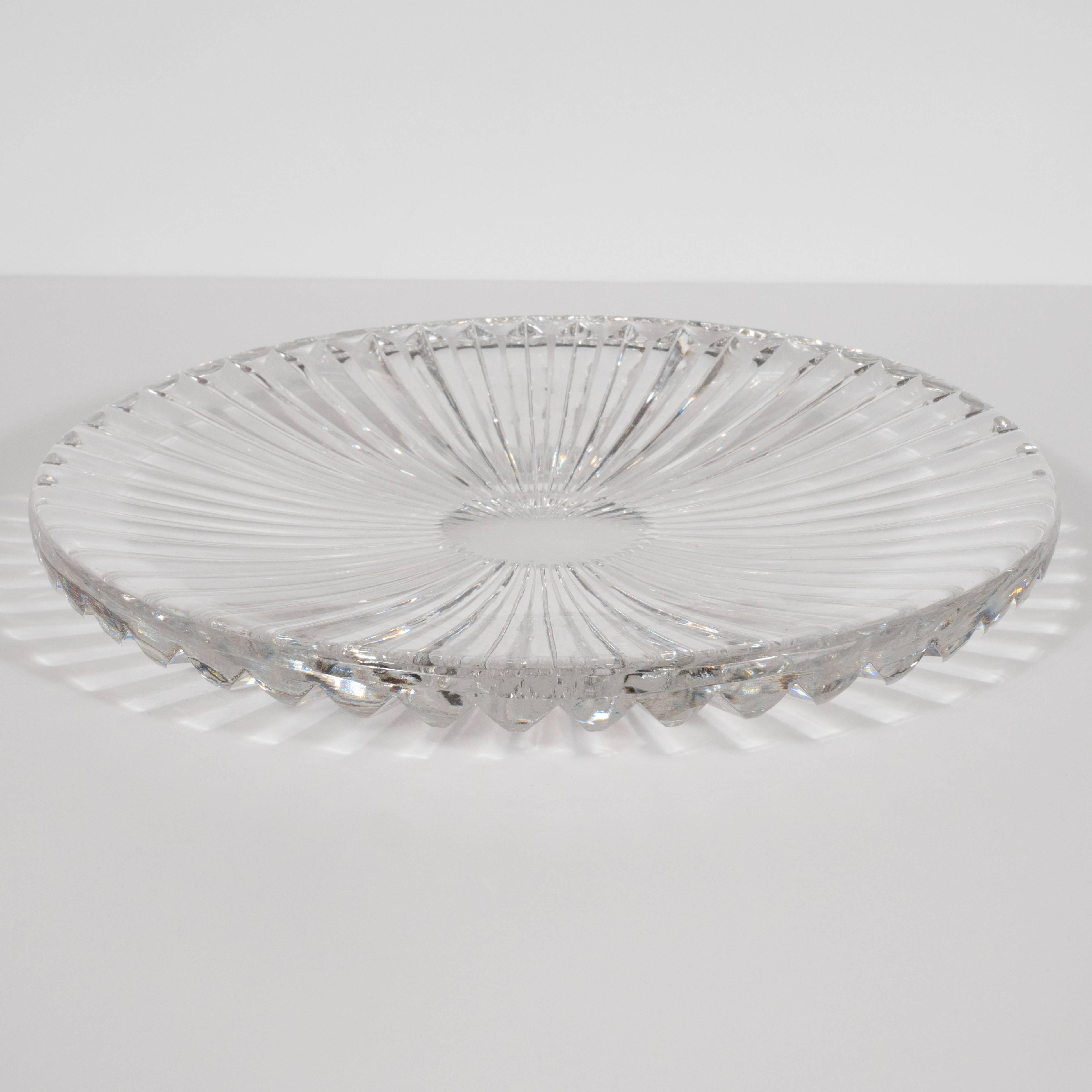 This sophisticated serving plate was realized in the United States, circa 1960. It features a sunburst pattern emanating from the center. The bottom has been incised with deep channels, which create myriad pentagonal forms circumscribing the