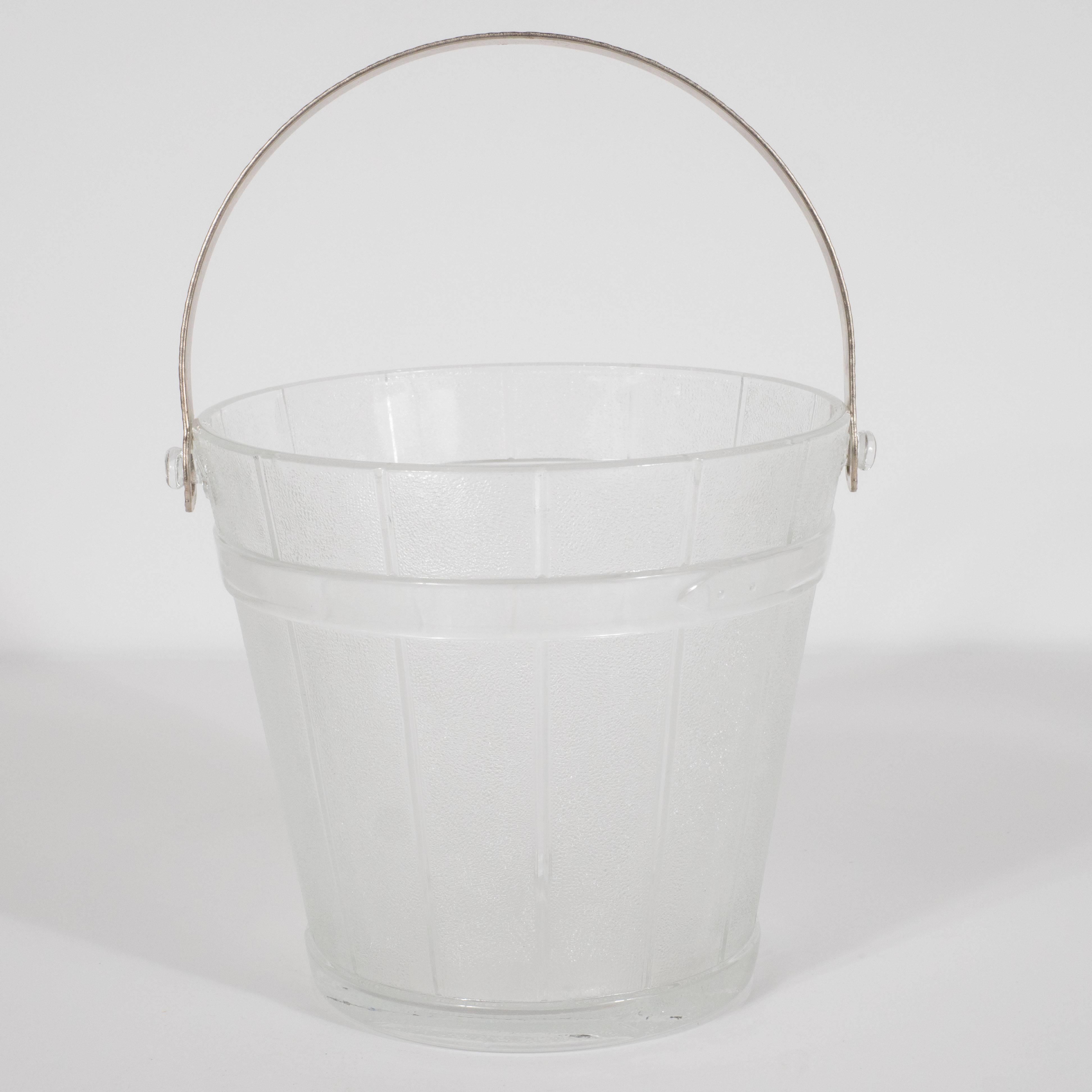 This sophisticated and stylish ice bucket was realized in the United States, circa 1930. Its form represents a stylized interpretation of a wooden water pail- an emblem of classical Americana, here elevated for the Machine Age. The wooden slats have