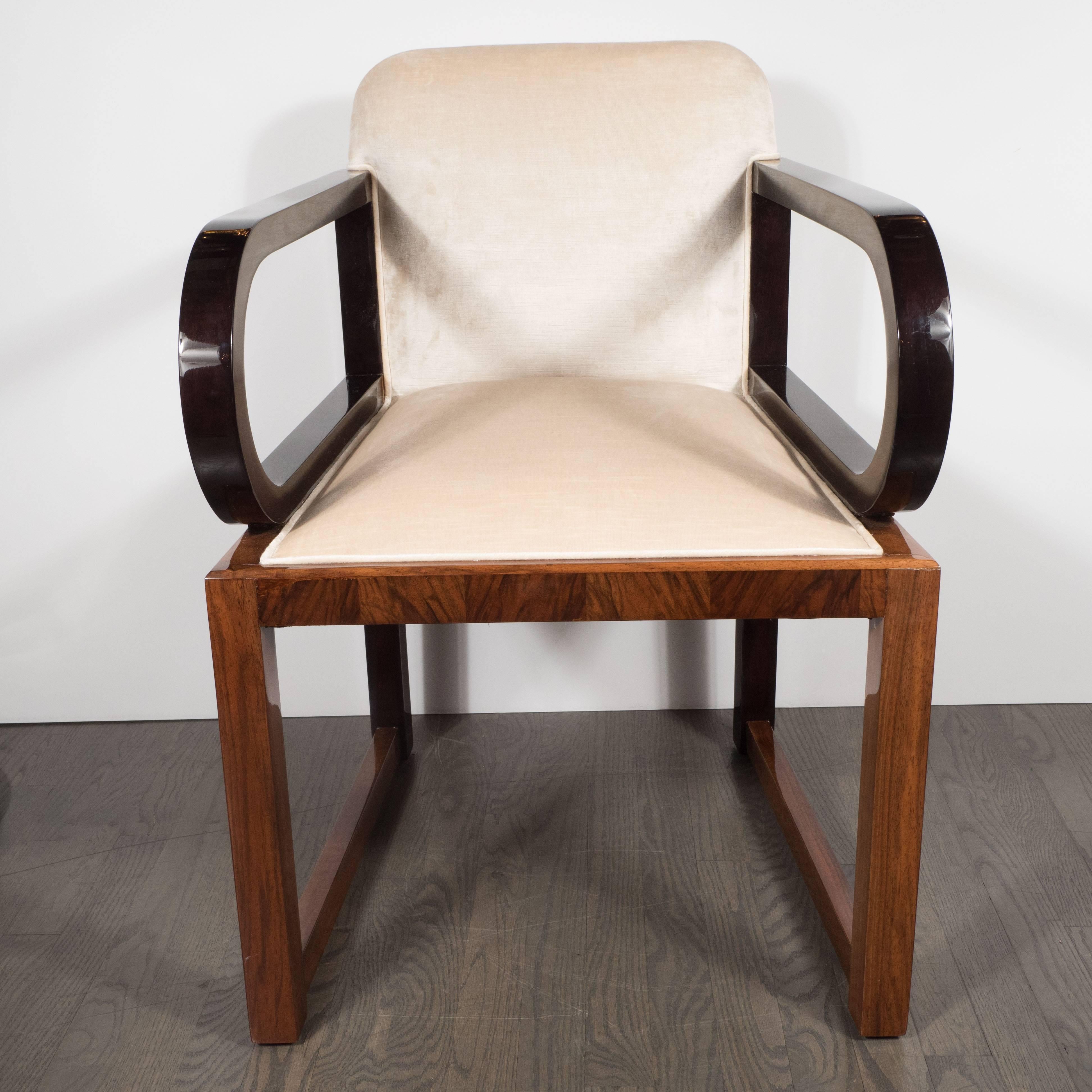 This gorgeous American Art Deco chair features streamlined arms in ebonized walnut, a material repeated on the stiles. The sable tones of the ebonized walnut offers a striking tonal contrast to the straight rectangular legs (as well as the apron) of
