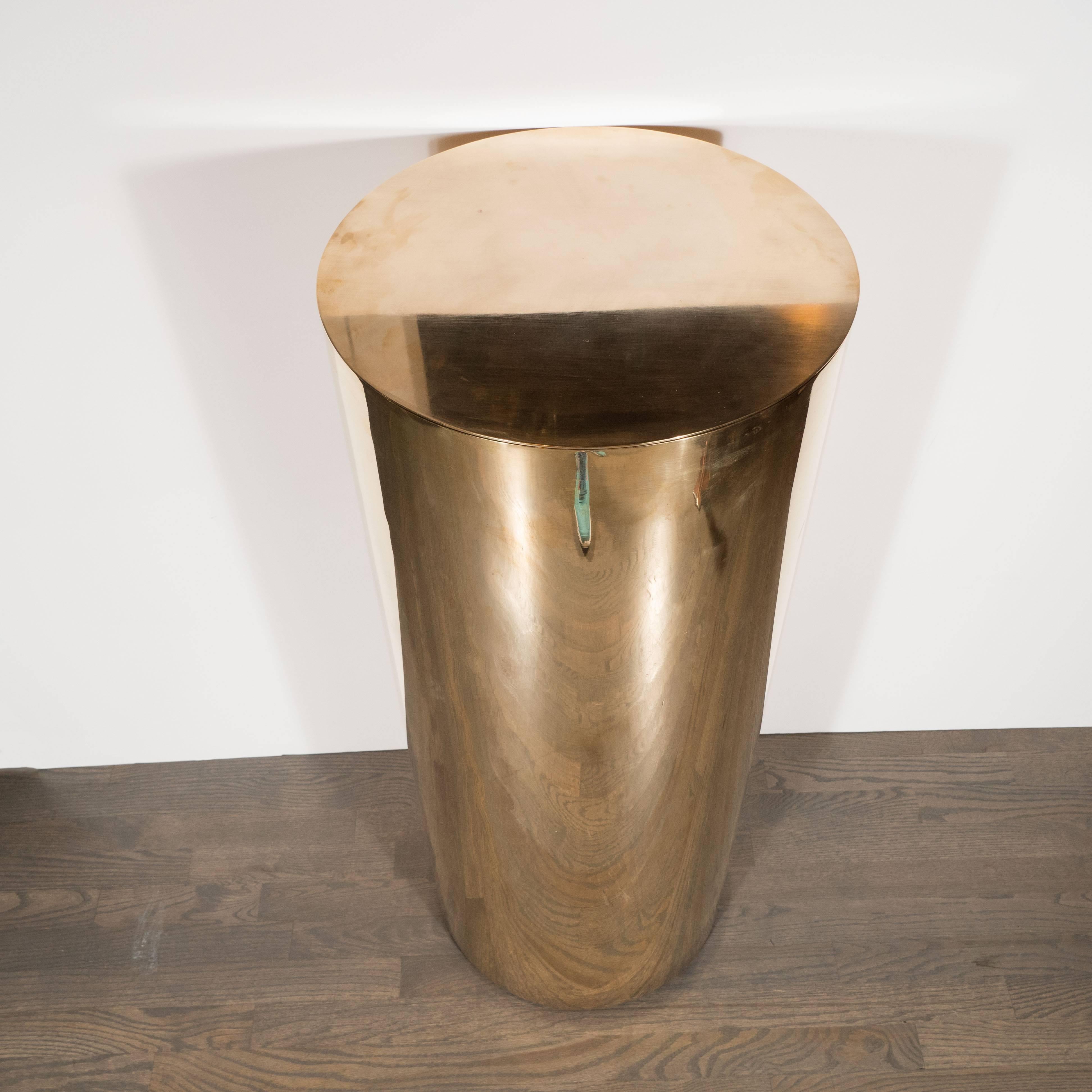This brass cylindrical pedestal was realized, in lustrous brass, in the United States, circa 1970. With its austere form, superlative construction, and luxurious materials, this piece would be a stunning addition to virtually any style of interior
