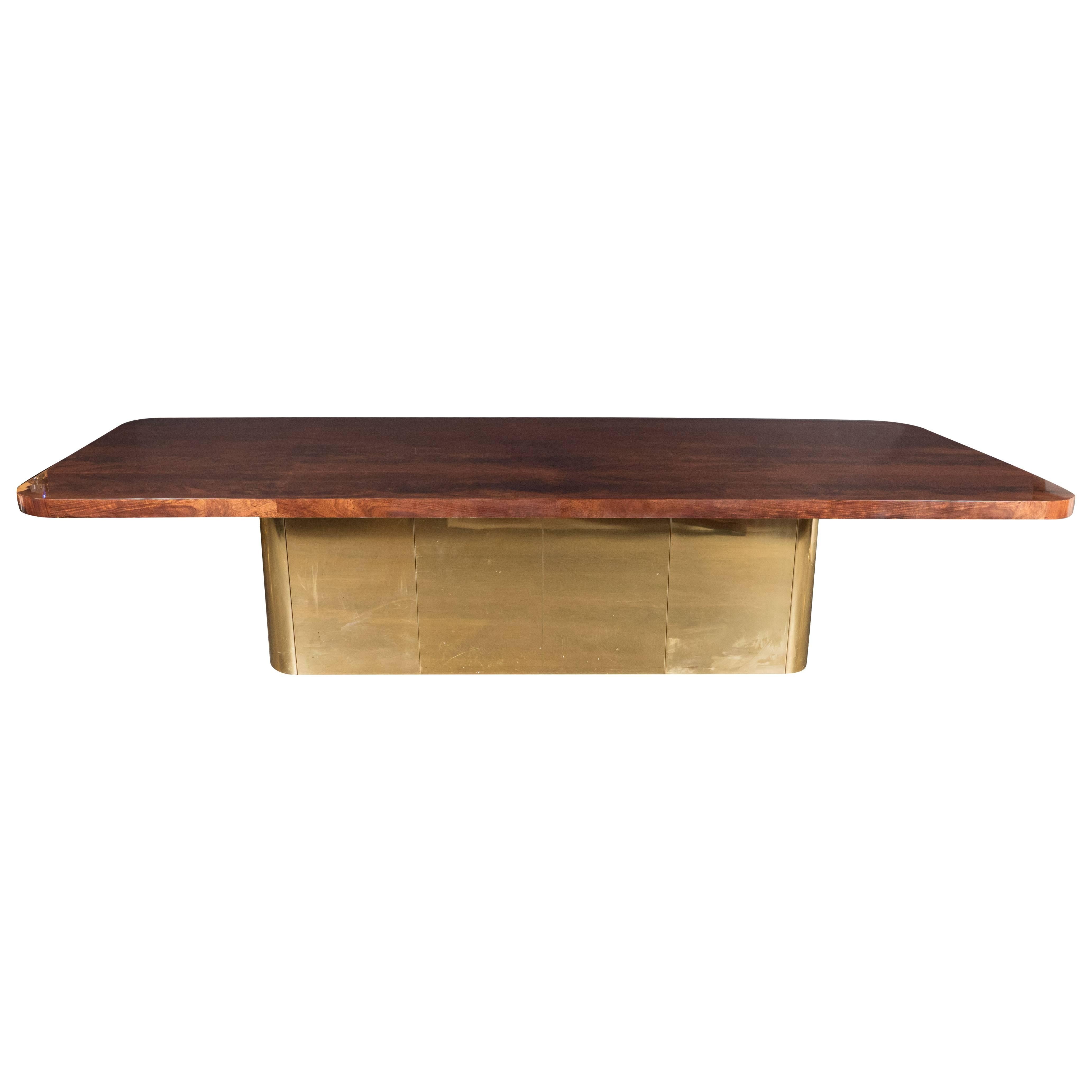 This monumental Mid-Century Modern dining table has a top constructed from gorgeous burled and bookmatched walnut and a rectangular streamlined form base with rounded edges in brass, creating a stunning material contrast to the woodgrain. This