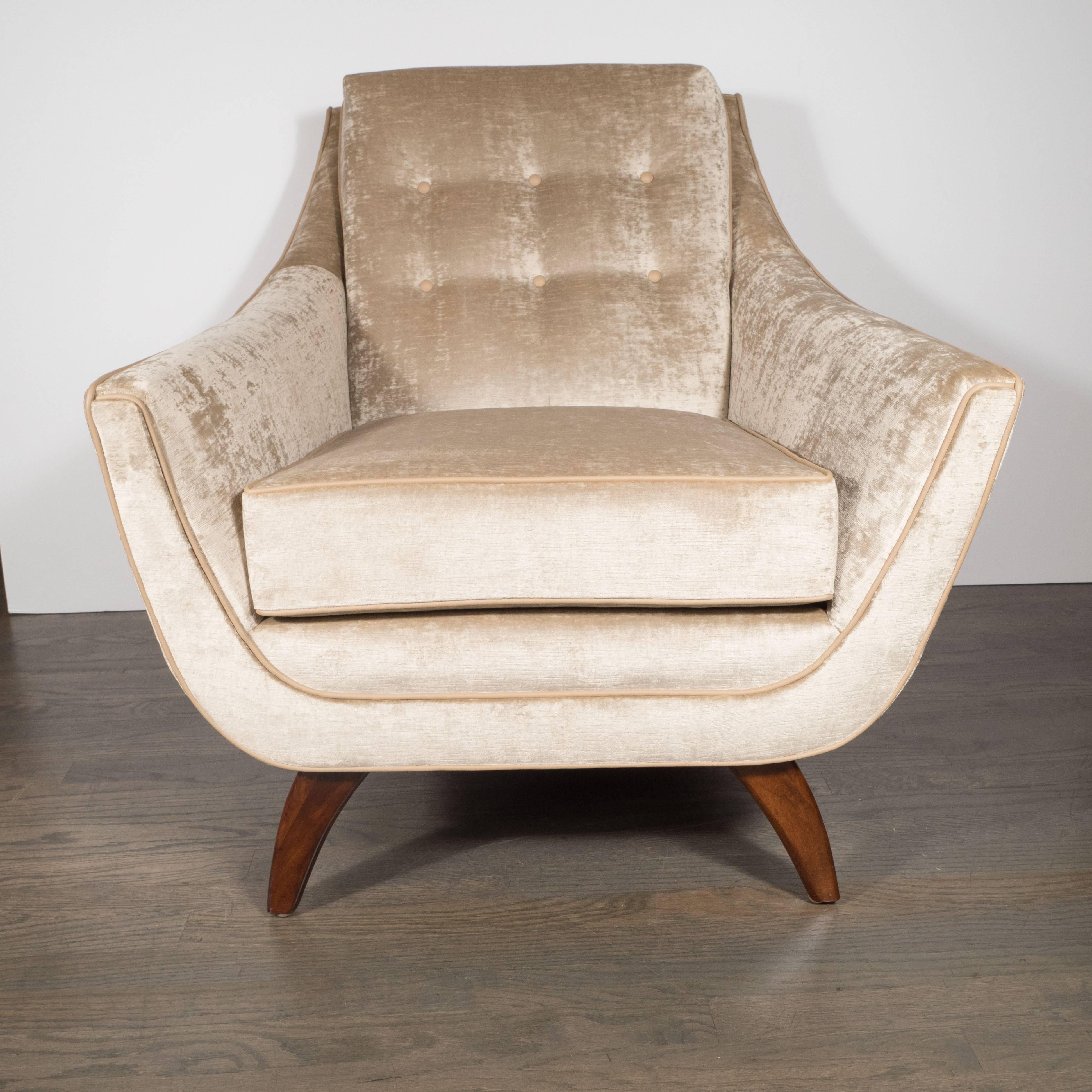 This refined Mid-Century Modern chair was realized in the United States, circa 1960. It offers the sinuous curves and superlative craftsmanship that collectors of the period prize, including champagne leather piping along the perimeter and button
