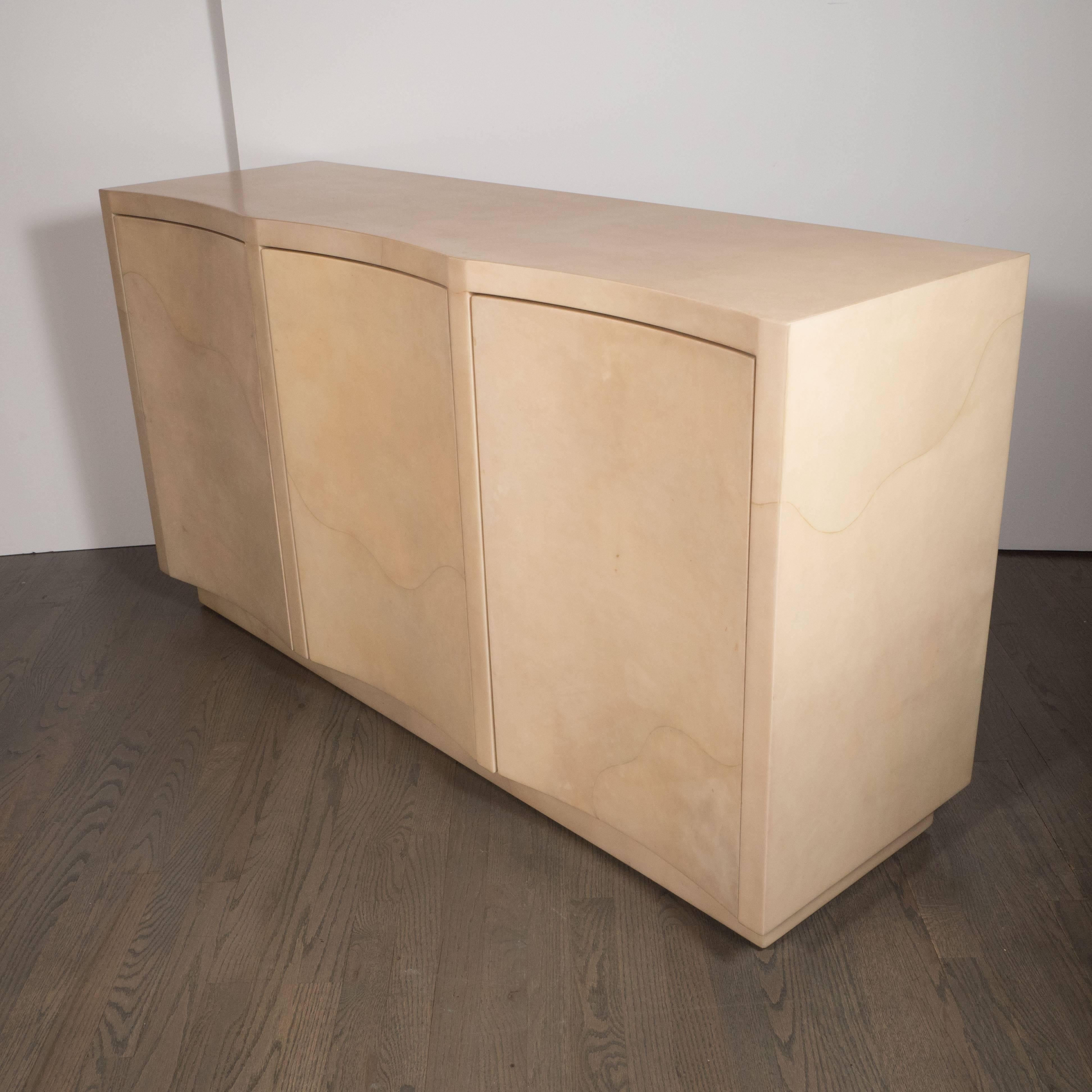 This stunning modernist cabinet illustrates the timeless appeal of excellent design. Composed of lacquered goat skin, the piece offers the color palate of bleached elm with variegated tones of tan and a texture suggestive of a quartz grain, with