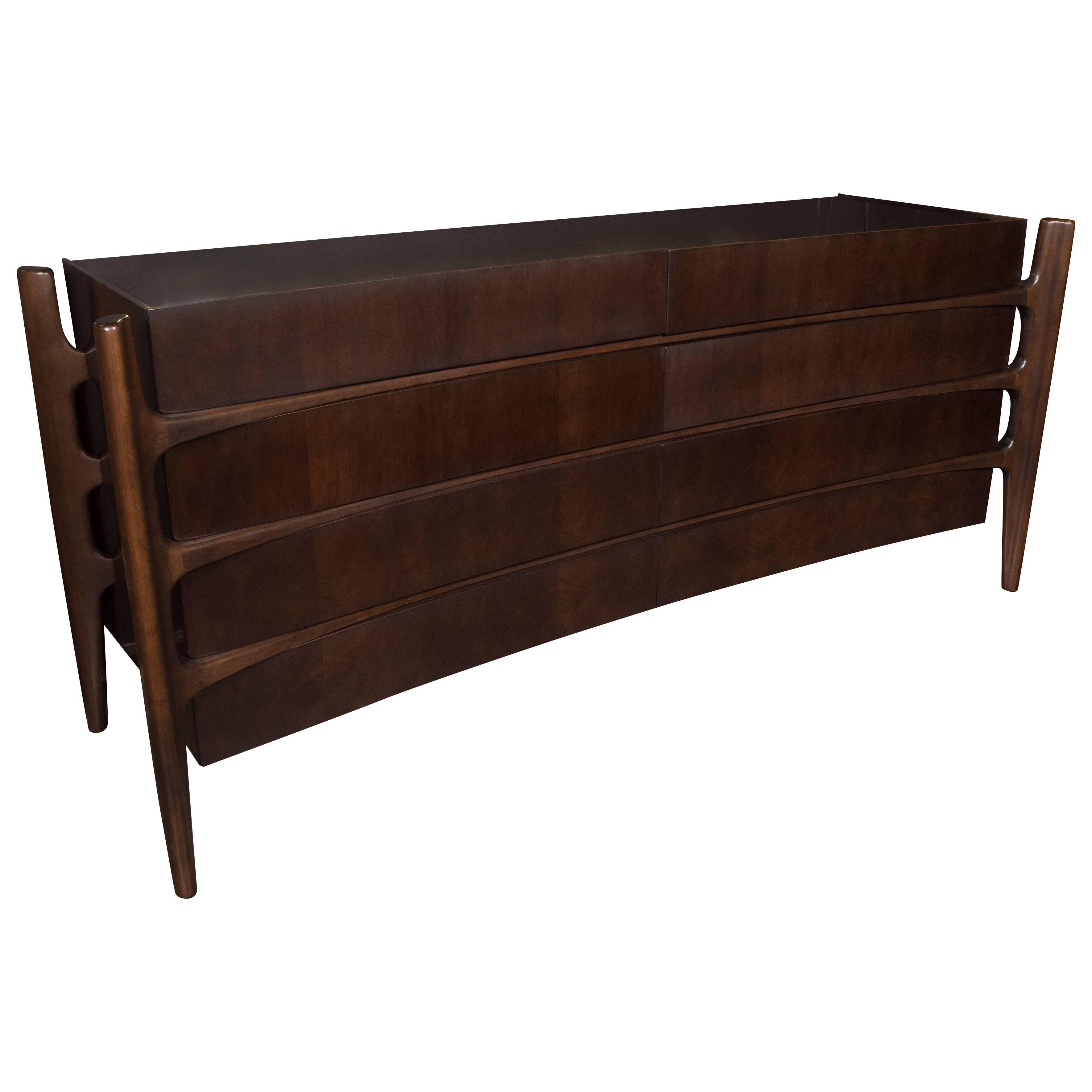 The celebrated Mid-Century Modern Swedish designer William Hinn realized this exceptional and rare eight-drawer walnut dresser, circa 1950. It features four splines, detached from the body of the cabinet, that descend into tapered legs. The splines