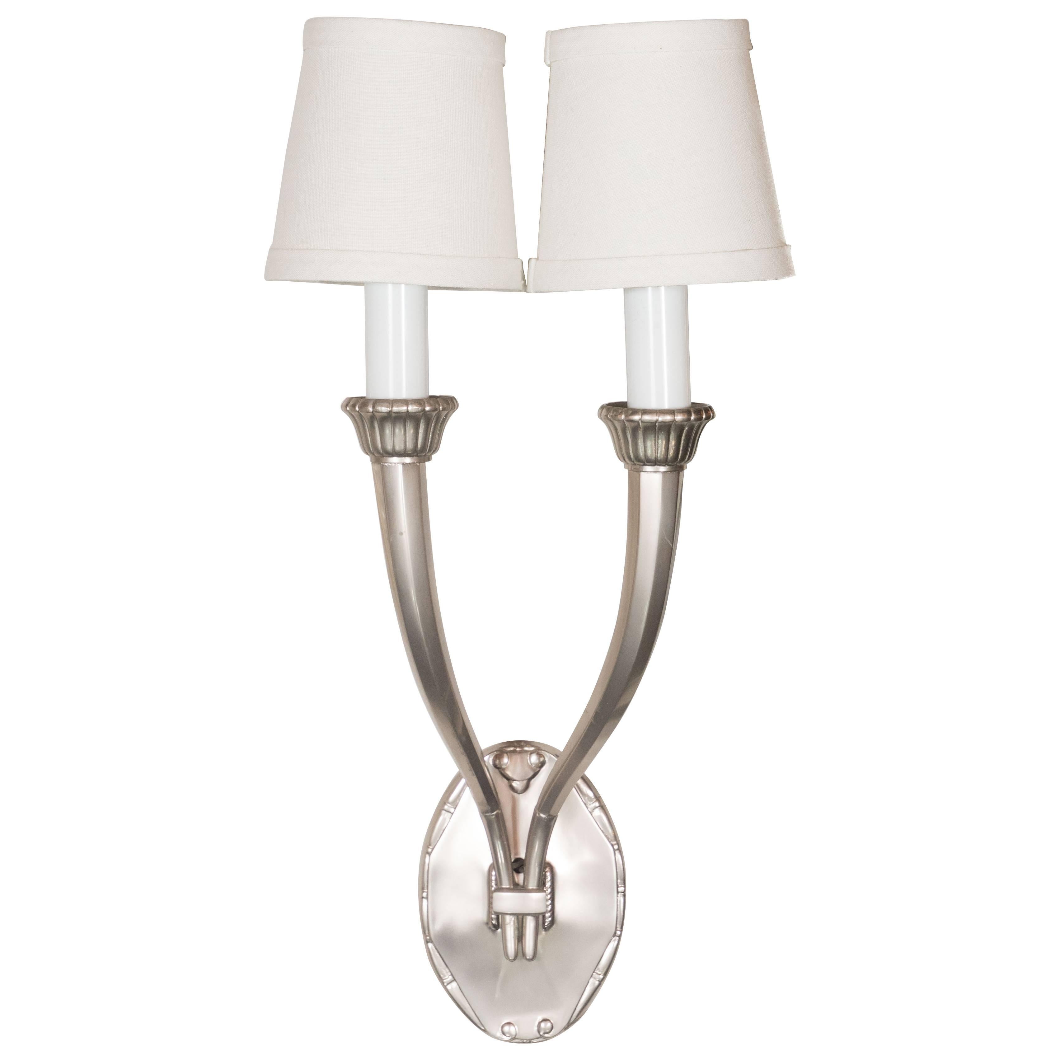 This stunning set of four Art Deco brushed nickel sconces features octagonal horn shaped arms that elegantly curve upwards from the rectangular support that attaches them to an ovoid shaped base. They culminate in a billowing reeded form at their