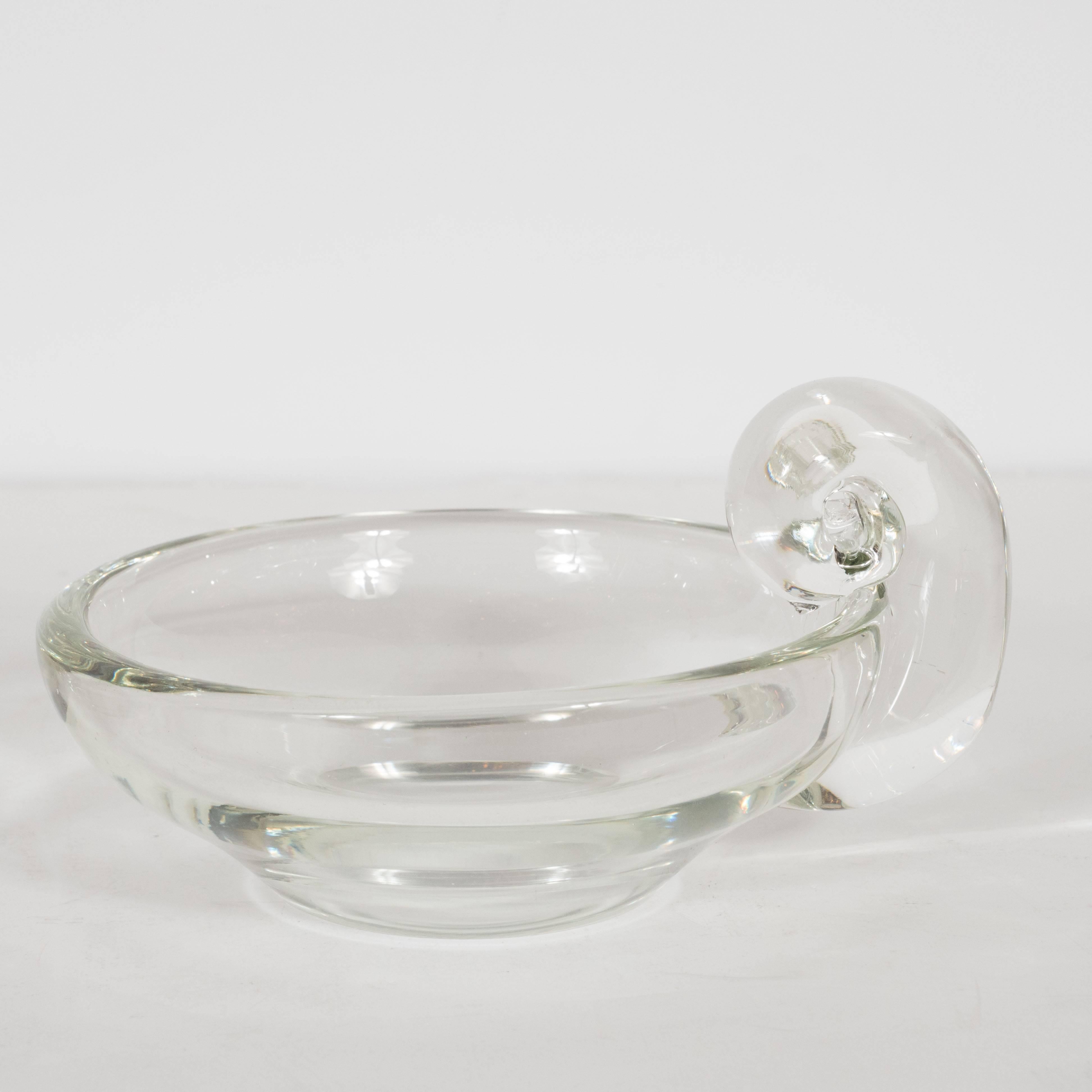 This refined pair of Mid-Century Modern bowls were handcrafted by the storied American glass studio, Steuben, circa 1960. They feature gently sloping sides and scroll style handles that resemble stylized ram horns. They would be perfect for