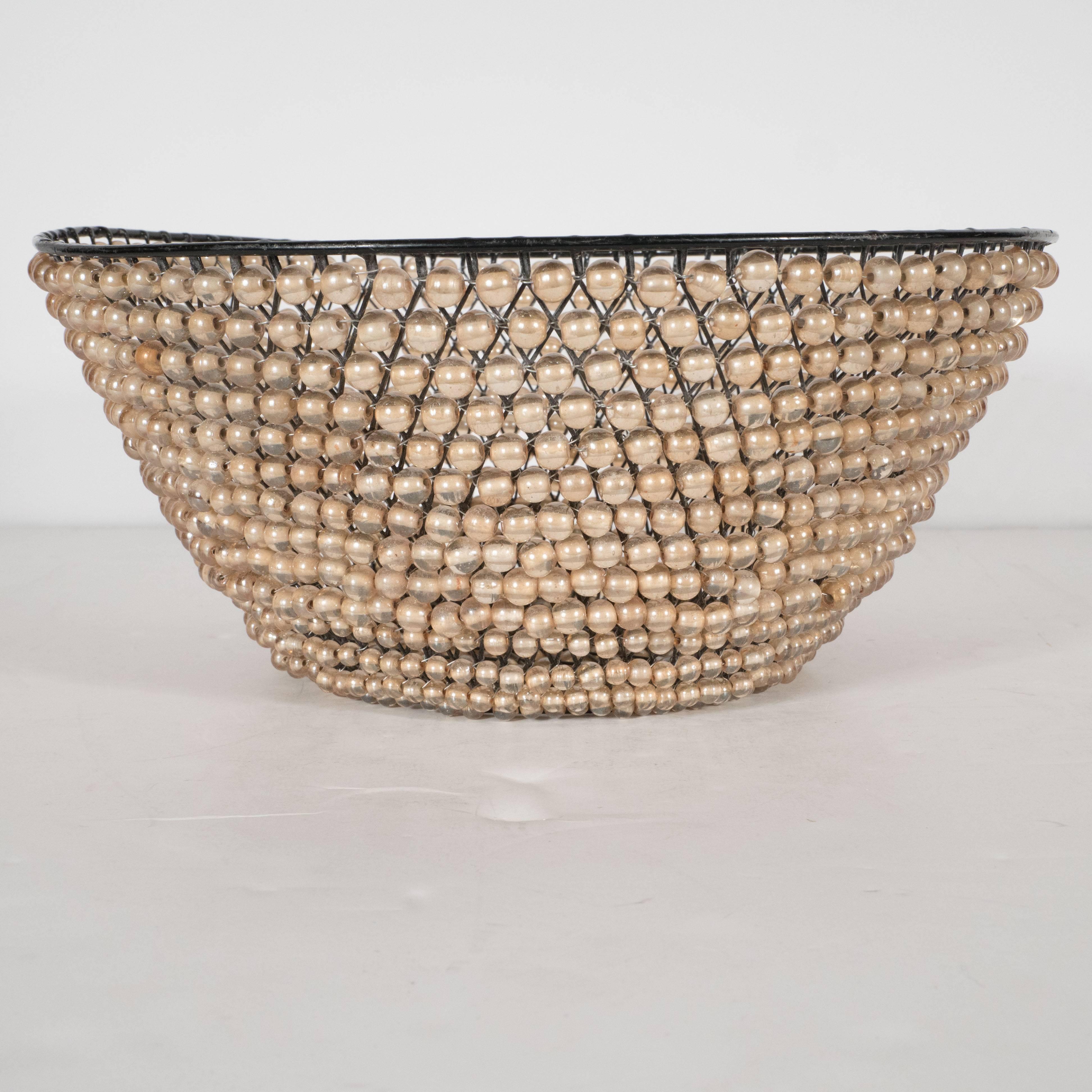 This sophisticated basket was realized by the esteemed contemporary American designer, Kim Seybert. It offers a lattice work metal frame from which an abundance of beads are suspended. The design recalls a flapper dress, recalling the sophisticated