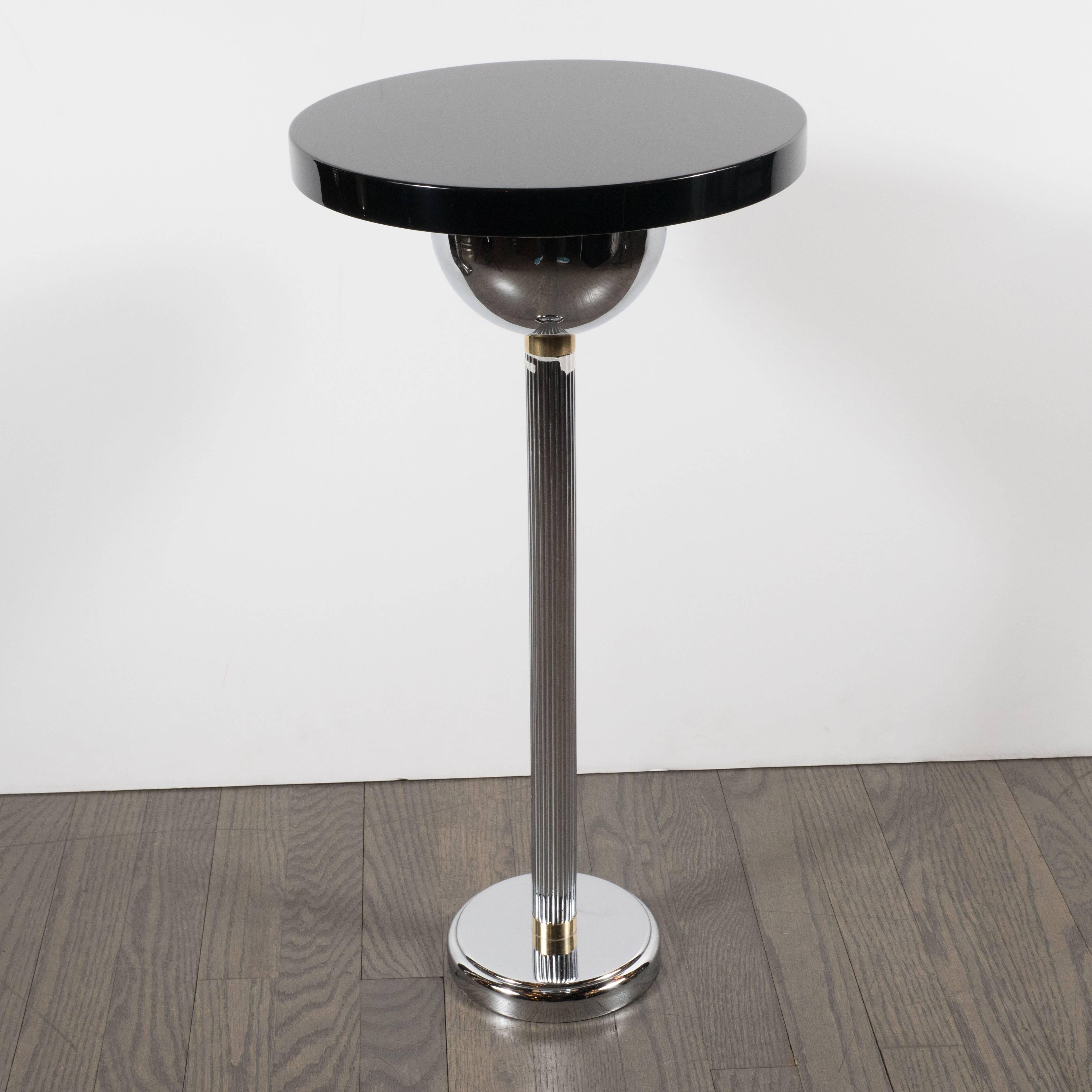 This refined Art Deco Machine Age Drinks table represents the unadorned elegance of great design at its essence. It features a lustrous black lacquer top supported by an inverted dome form, a reeded chrome columnar stem and a skyscraper style base