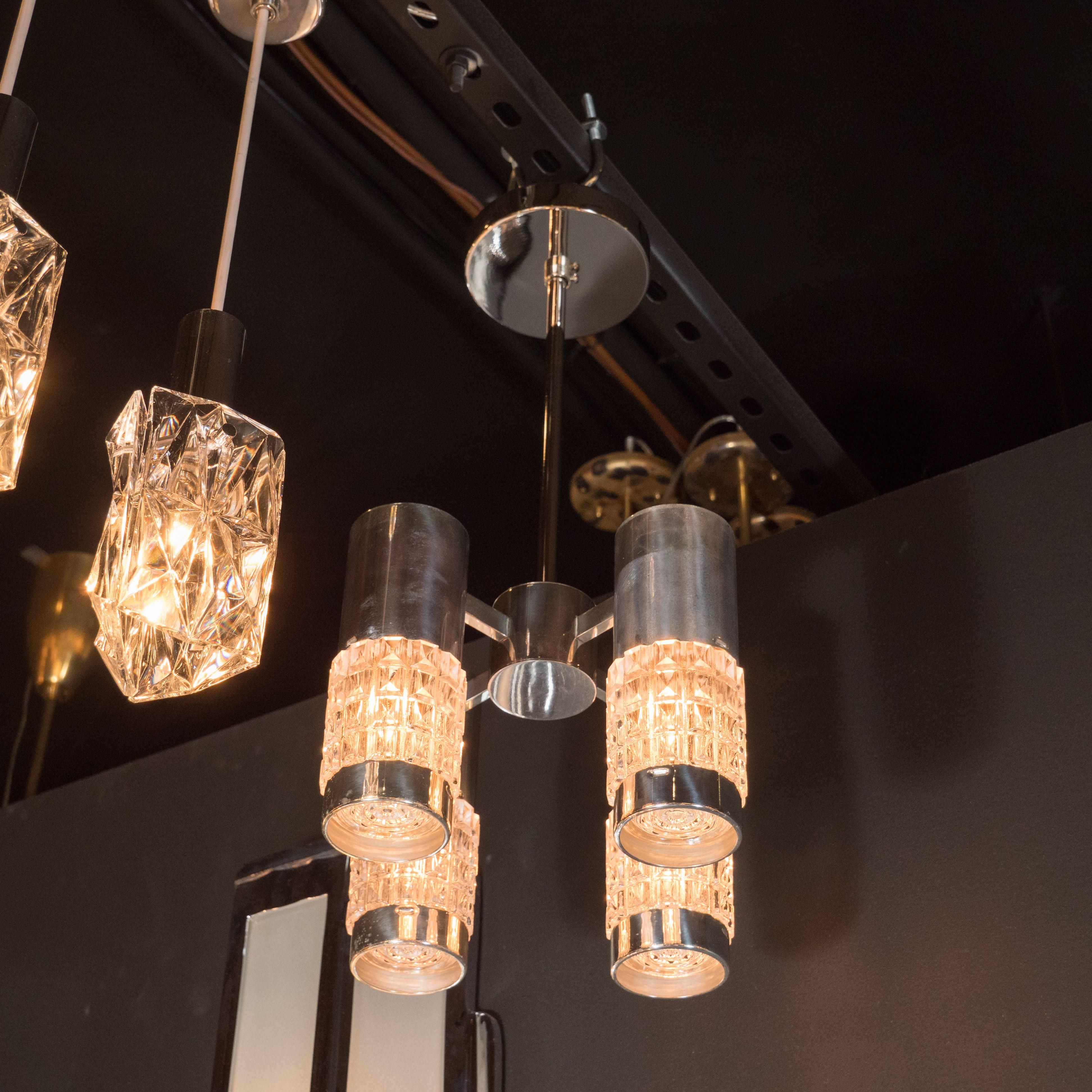 Questo irresistibile lampadario Mid-Century Modern è stato realizzato in Germania, intorno al 1950. Rappresenta un esempio eccezionale dell'epoca e del luogo. Un'asta cilindrica scende da un baldacchino circolare, dove incontra una forma centrale,