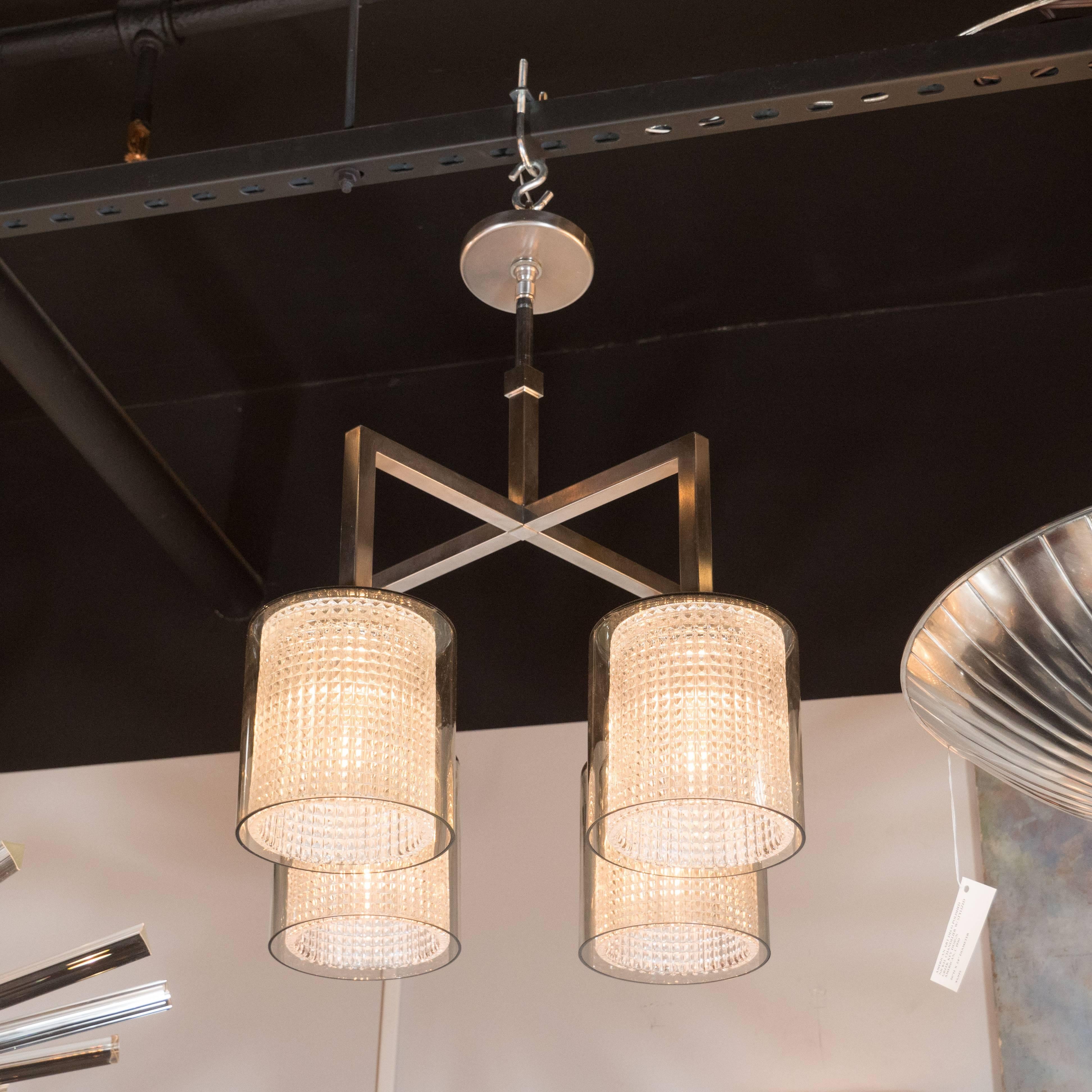 This refined chandelier was realized by the esteemed Swedish designer Carl Fagerlund for Orrefors, circa 1960. It features a central rectangular stem, with a cube embellishment near its top, from which four arms extend outwards where they ascend at