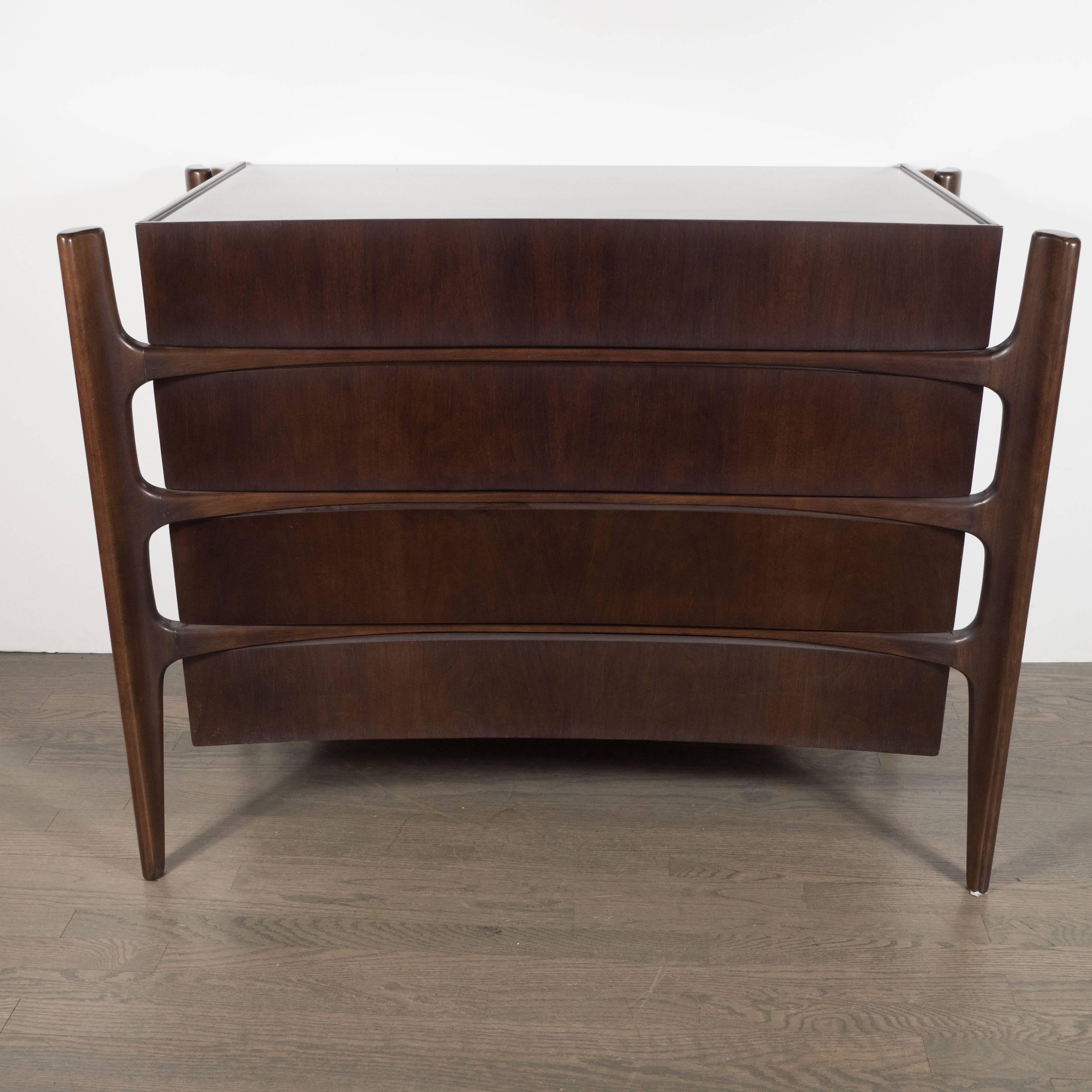 The celebrated Mid-Century Modern Swedish designer William Hinn realized this exceptional and rare four-drawer walnut dresser, circa 1950. It features four splines, detached from the body of the cabinet, that descend into tapered legs. The splines