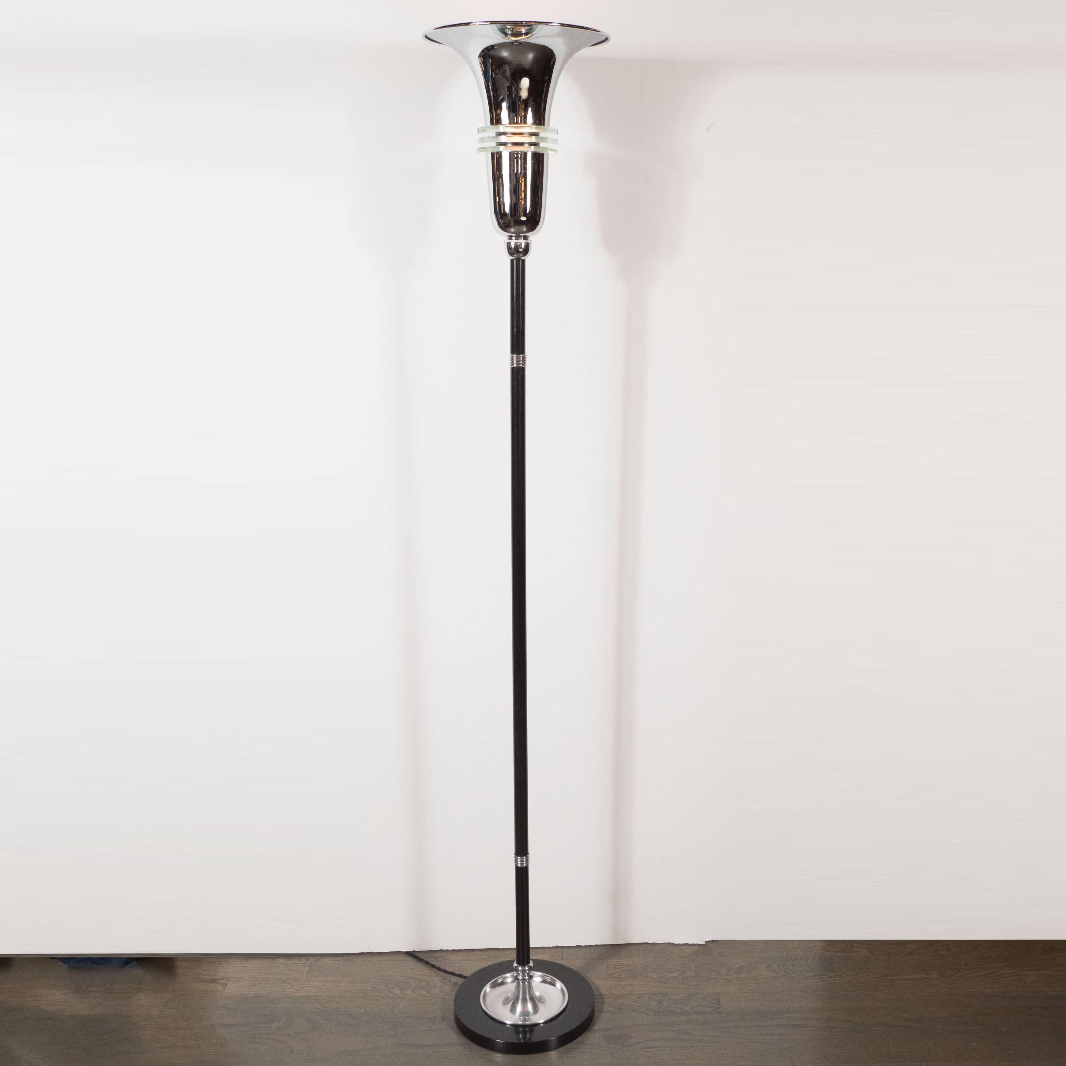 This elegant Art Deco machine age floor lamp was realized in the United States, circa 1935. It offers a trumpet form shade in lustrous chrome, banded in its centre by three tiers of cut-glass. The rod is composed of black enamel with banded chrome