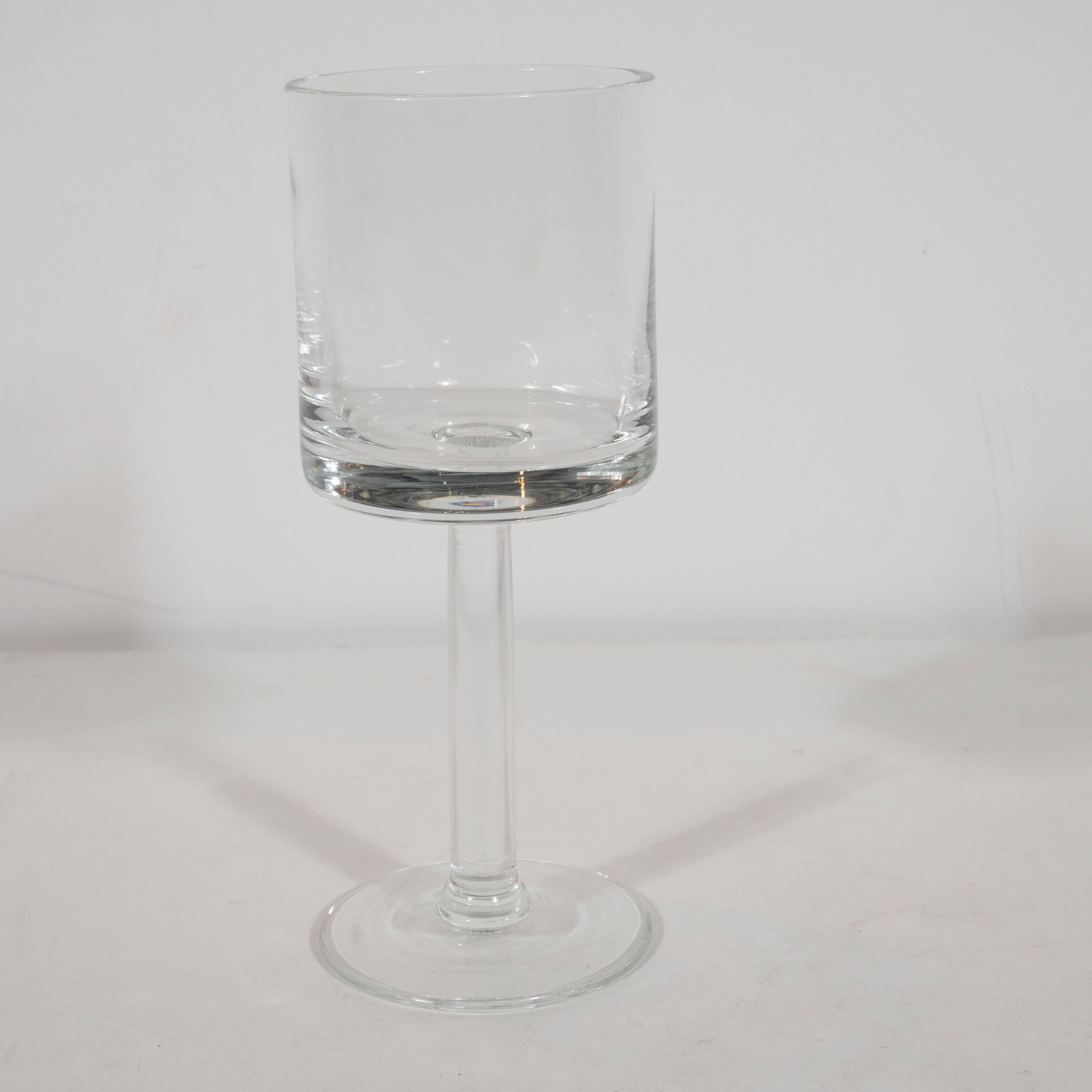 This refined set of eight glasses was realized by the illustrious American designer Calvin Klein, circa 1980. They embody Klein's signature aesthetic of seductive minimalism translated to glassware. Each glass has a circular base, a cylindrical