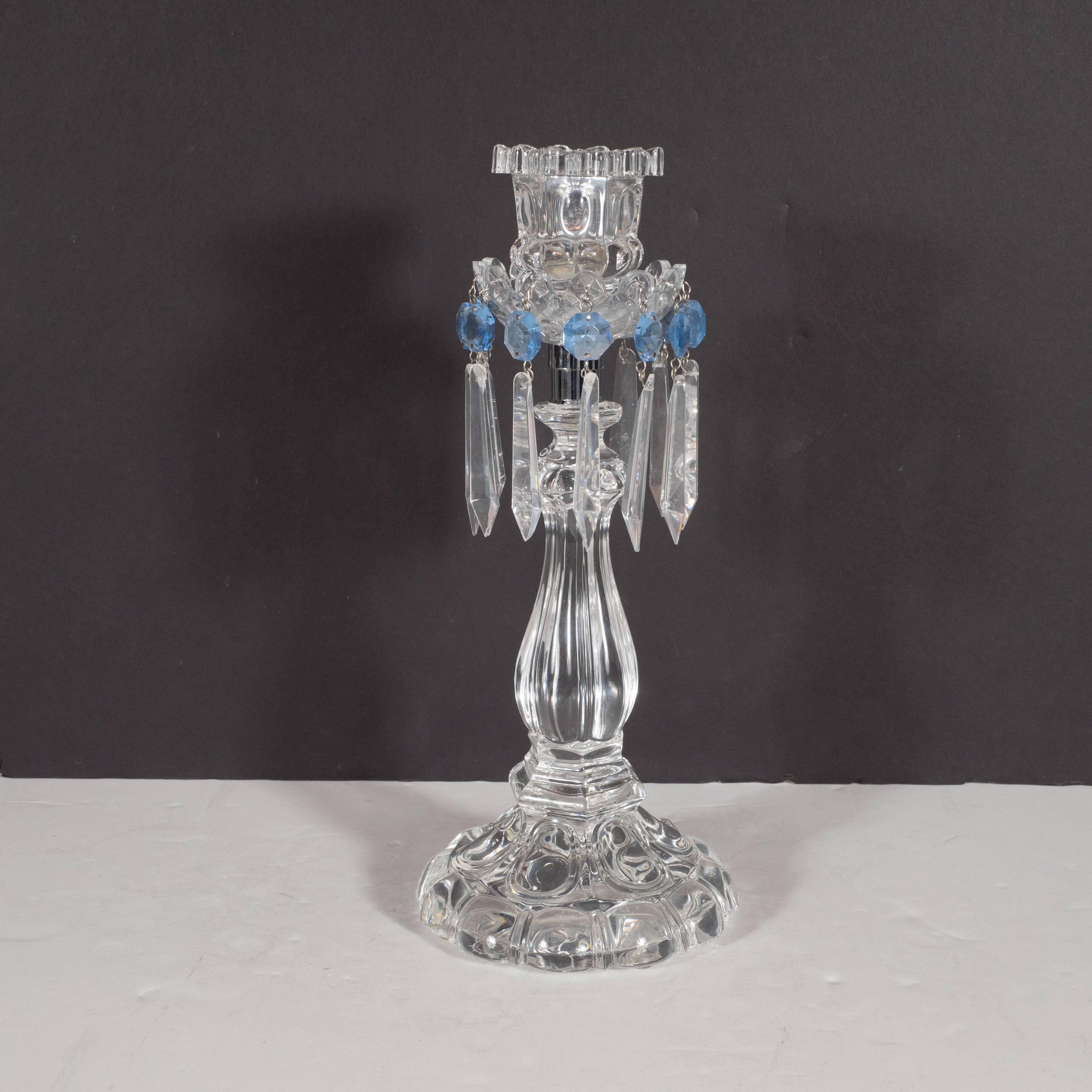 This exquisite pair of Mid-Century Modern crystal girandoles were realized by the esteemed French luxury house Baccarat. They feature reeded columnar central stems with a diamond etched bobeche below a scalloped top. The columns connect to the