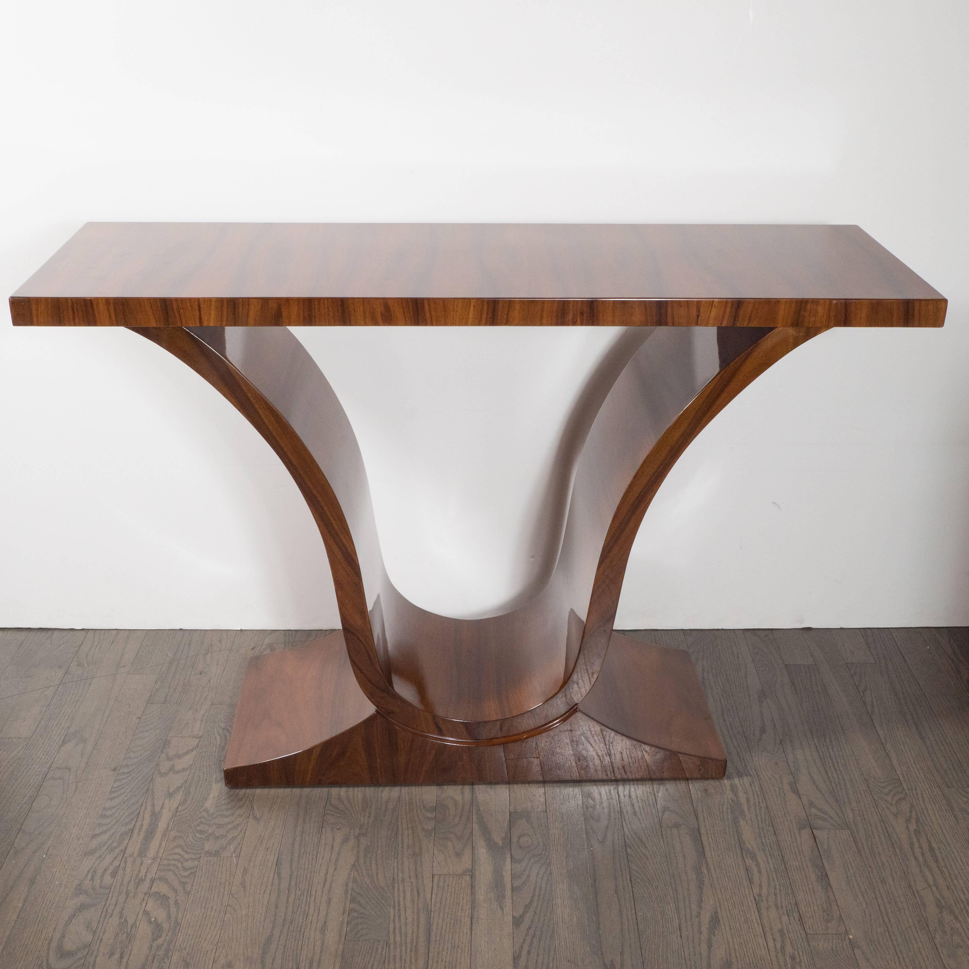This refined console table was realized in France, circa 1935, at the height of Art Deco. It features a classically inspired urn form consisting of a single undulating curve, inspired by classical Greek design, in bookmatched walnut that offers a