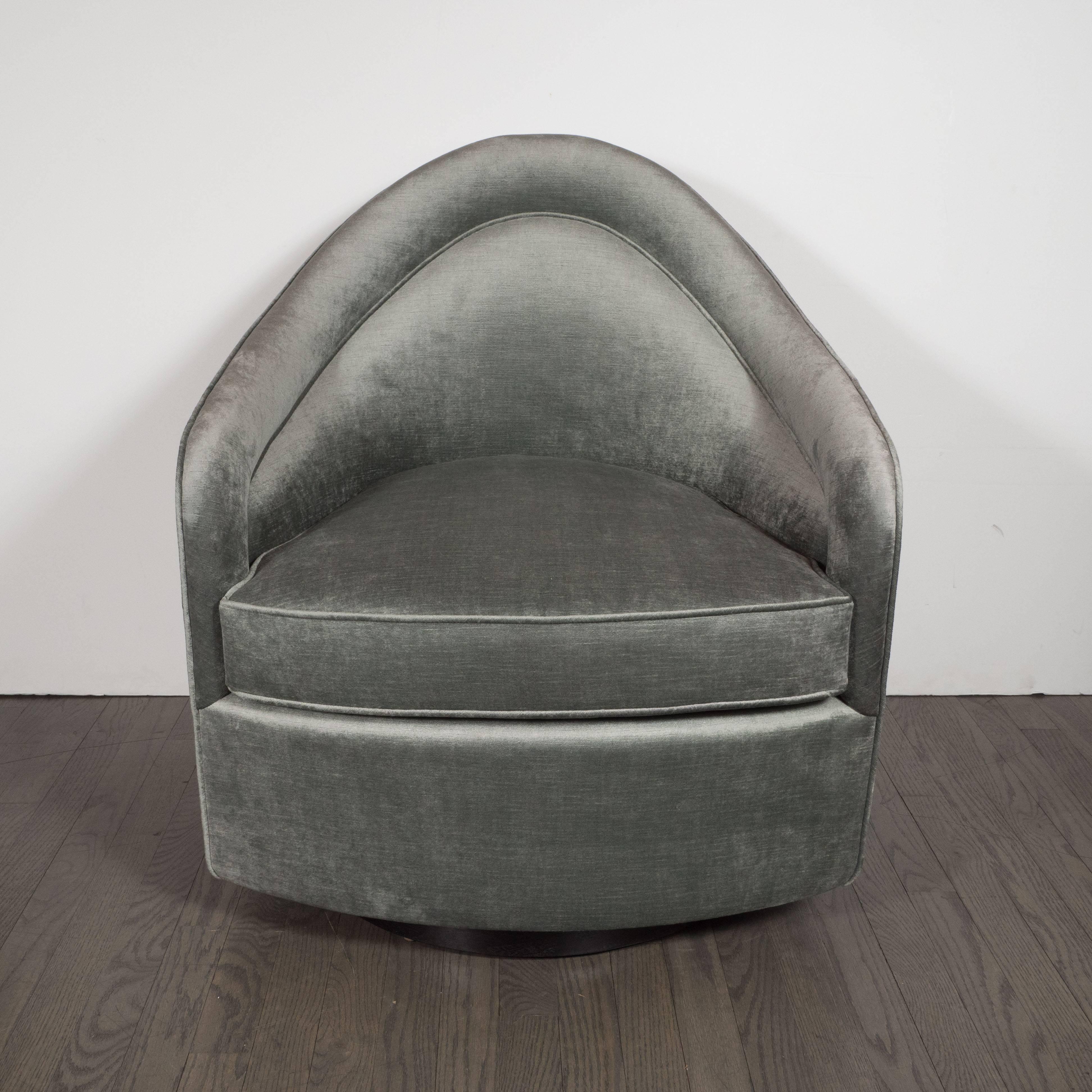 This sophisticated Mid-Century Modern swivel chair was realized by the esteemed American designer, Milo Baughman, circa 1970. It features an undulating curved back with arm supports that gently rise culminating in a central arched form. The shape of