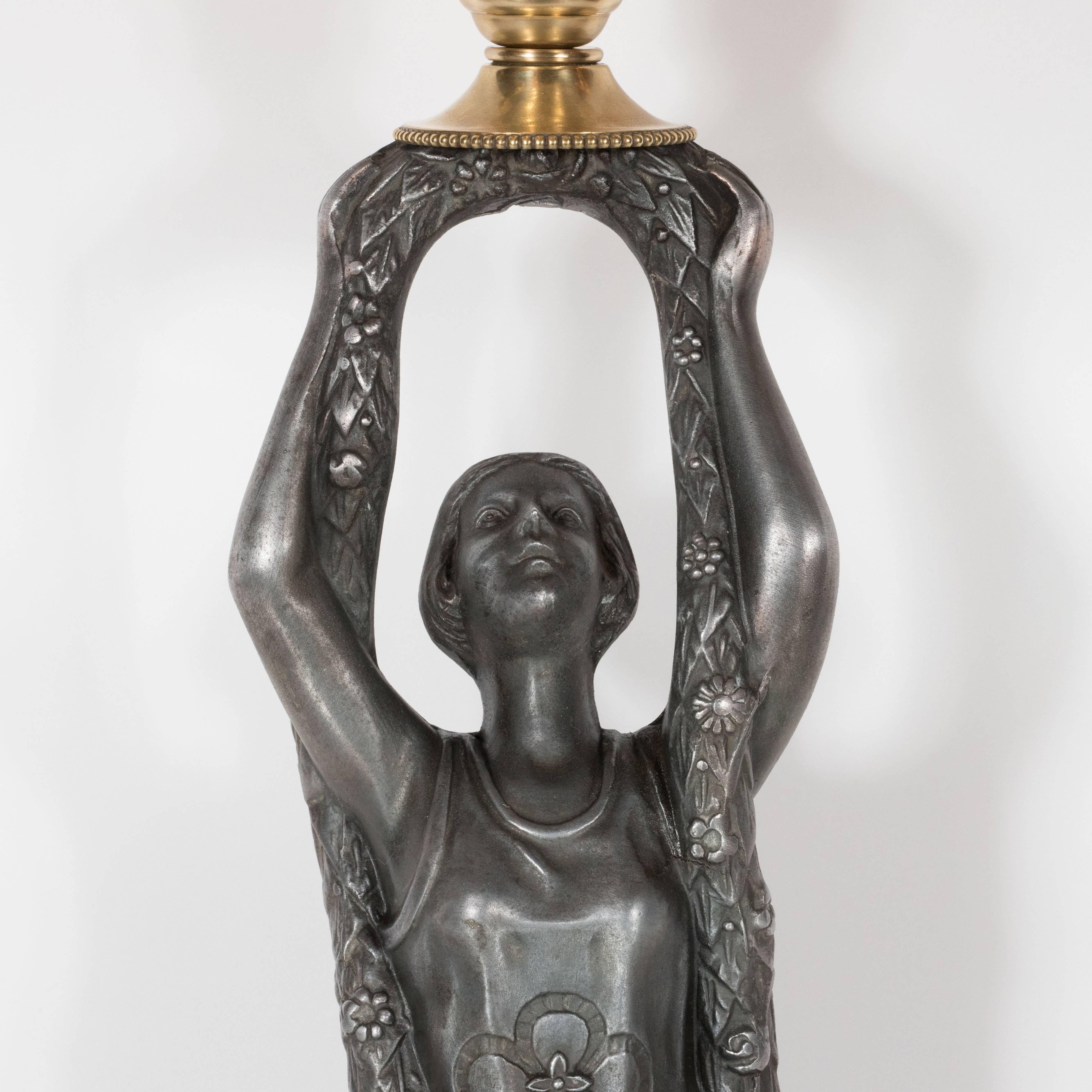 This rare and original Art Deco flapper lamp was realized in the United States, circa 1930. In the center of the piece, a lady in a 1930s style dress- inscribed with a floral decoration- kneels on a beveled base with a geometric cubist patterned