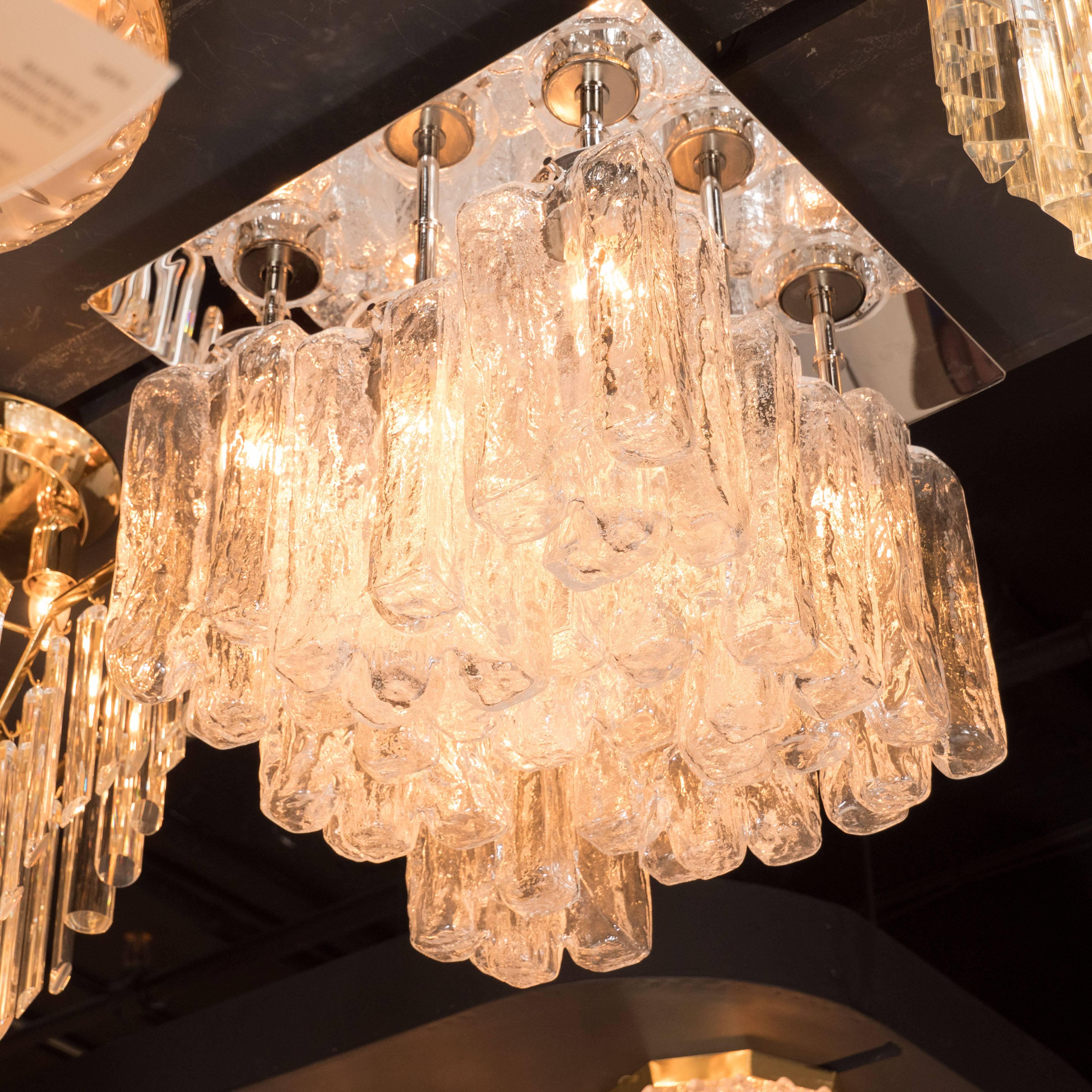 This sophisticated chandelier marries old world craftsmanship with contemporary design to a stunning effect. It features nine block form shades, consisting of a wealth of conjoined organic rectangular forms offering a subtle translucence. Crafted in