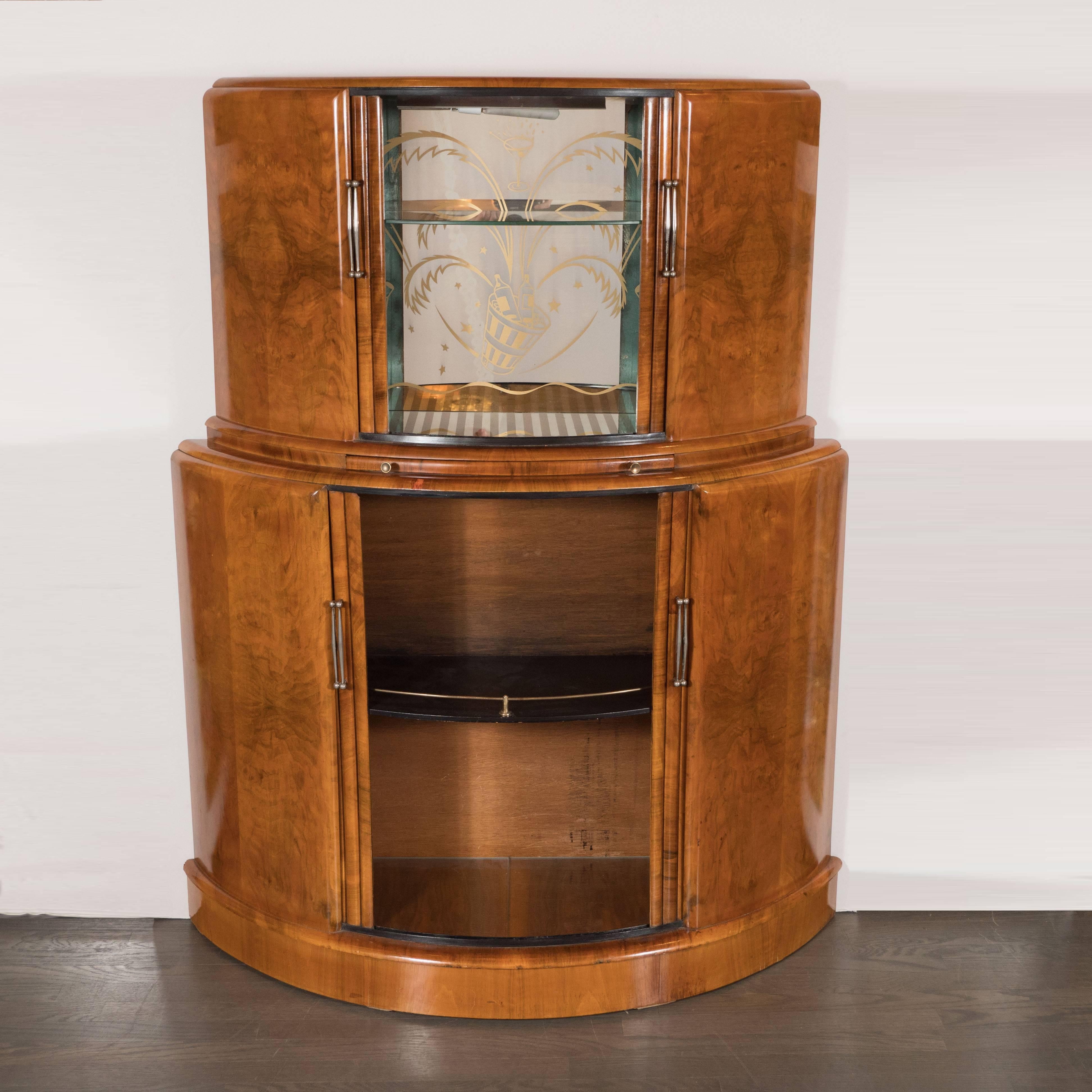 This Art Deco streamlined Skyscraper style tambour bar cabinet was realized in the England, circa 1935. It offers a tiered demilune form with two spacious compartments. The lower compartment has a black enamel shelf with a brass rail, while the