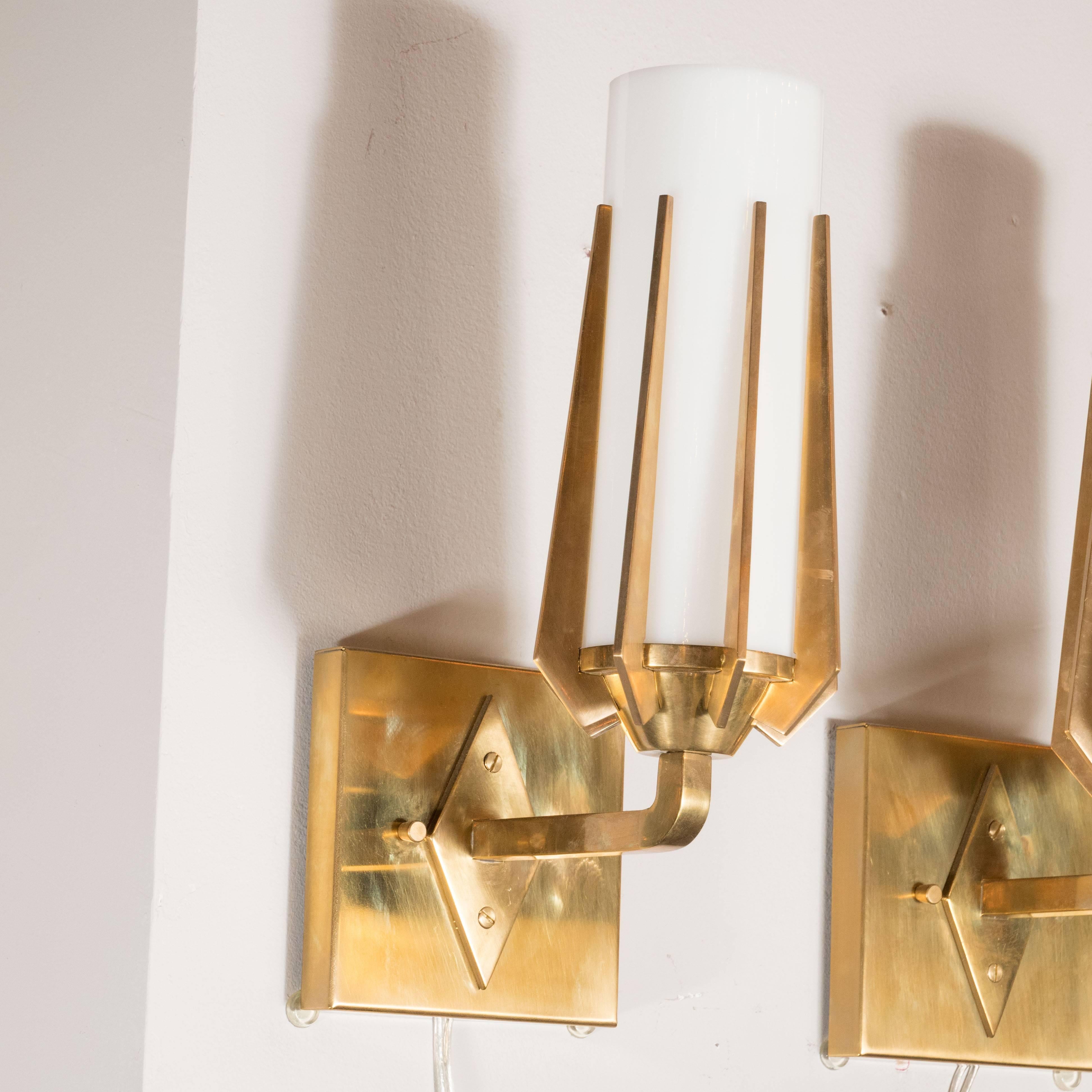 This stunning and dramatic pair of brass and milk glass sconces were realized in Italy, circa 1960, in the manner of Gio Ponti. They feature an abundance of tapered supports that are beveled at their bases that support cylindrical shades in white