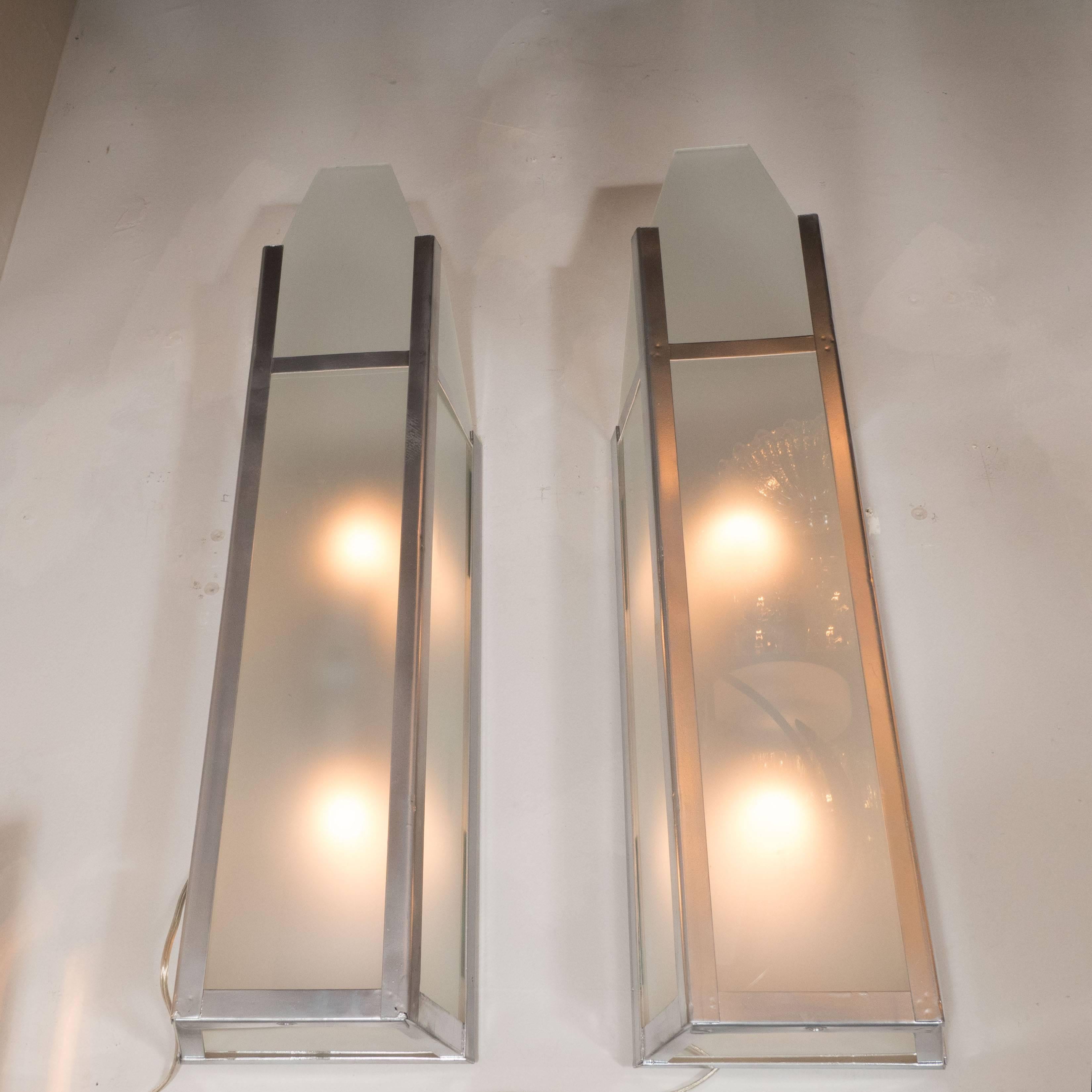 This sophisticated pair of sconces originally hung in the in the iconic Tower Theatre in Chicago. They features a rectangular form with frosted glass shades supported by a polished aluminum frame. With their skyscraper style design and industrial