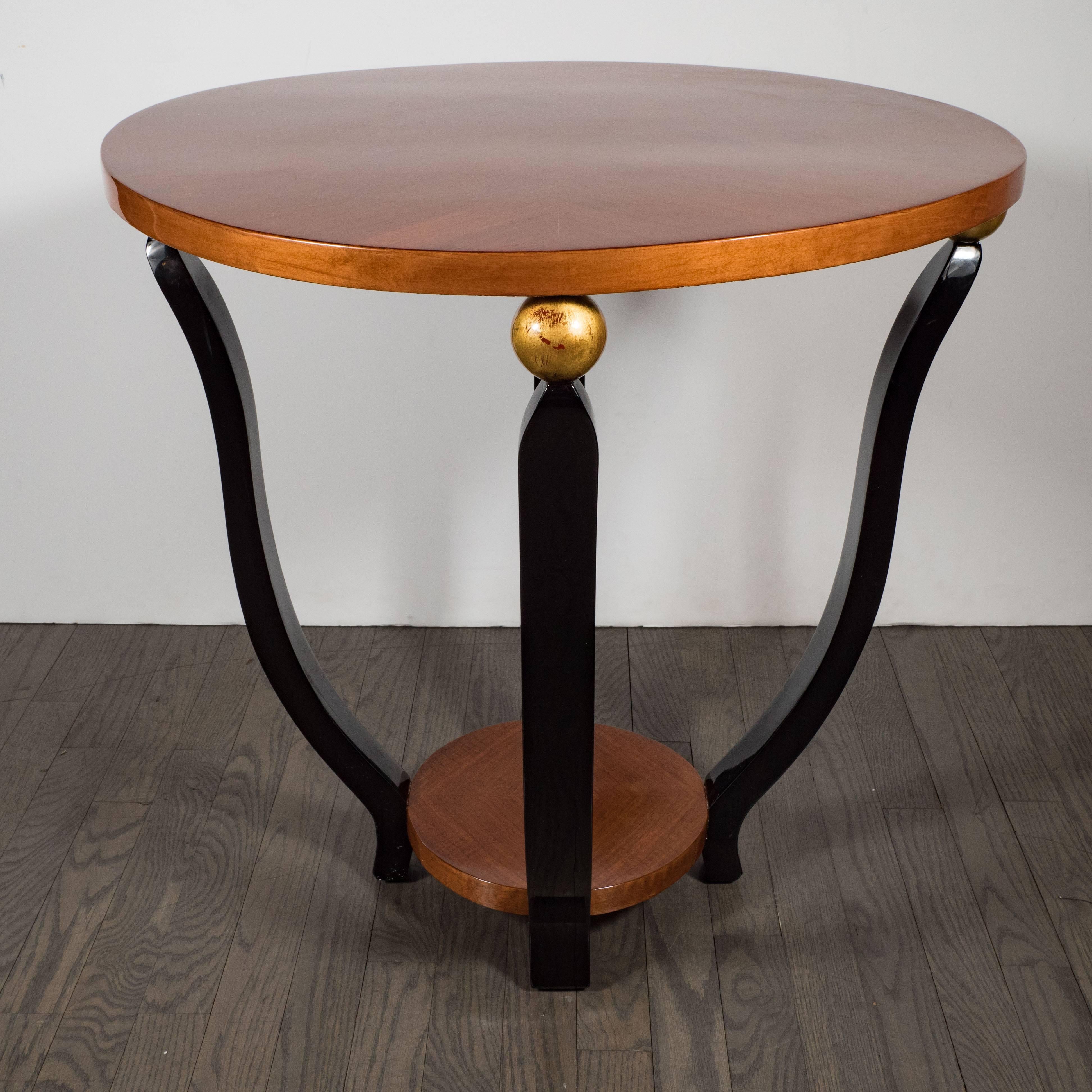 This elegant Gueridon table was realized in France, circa 1935 at the height of Art Deco. It features two circular tiers composed of bookmatched walnut connected by undulating supports finished in black lacquer that culminate in a orbital