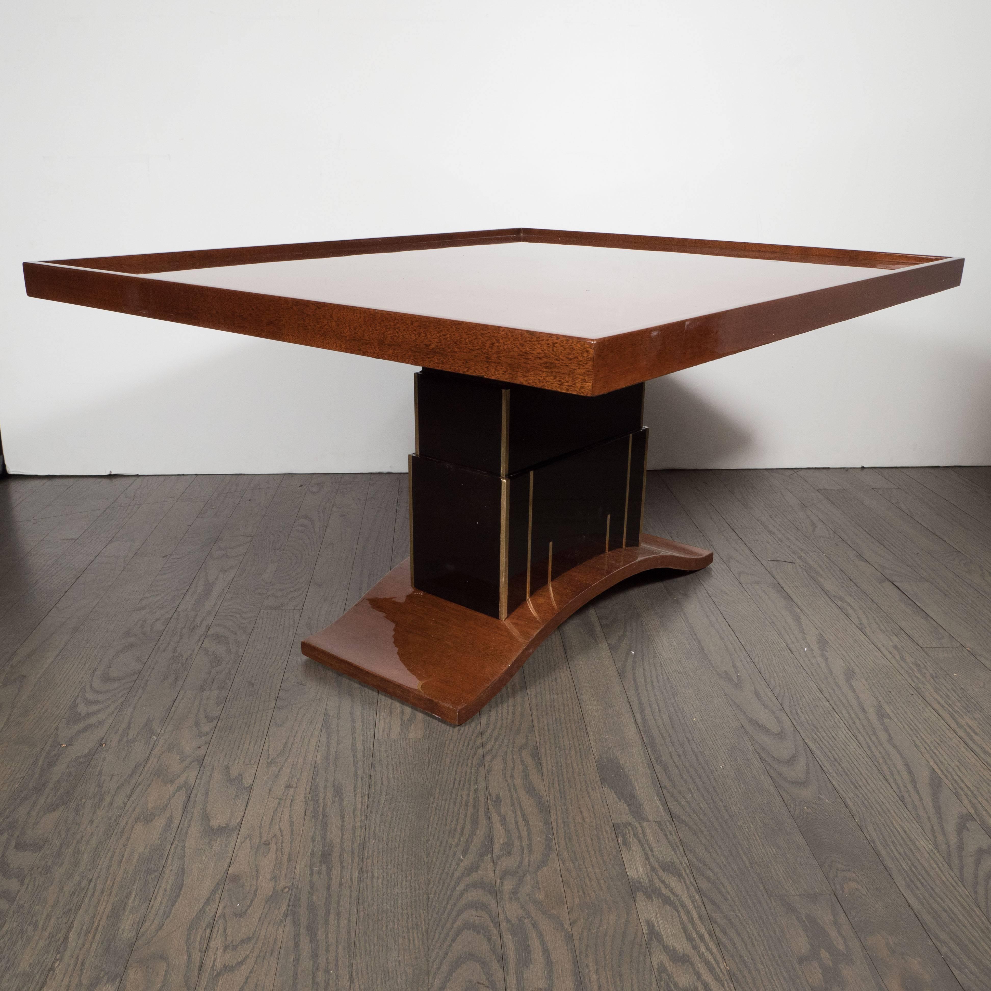 This stunning Art Deco skyscraper style occasional table was realized in the United States, circa 1935, at the height of Art Deco. It features a top consisting of walnut with a bookmatched mahogany border and a raised perimeter. The skyscraper style