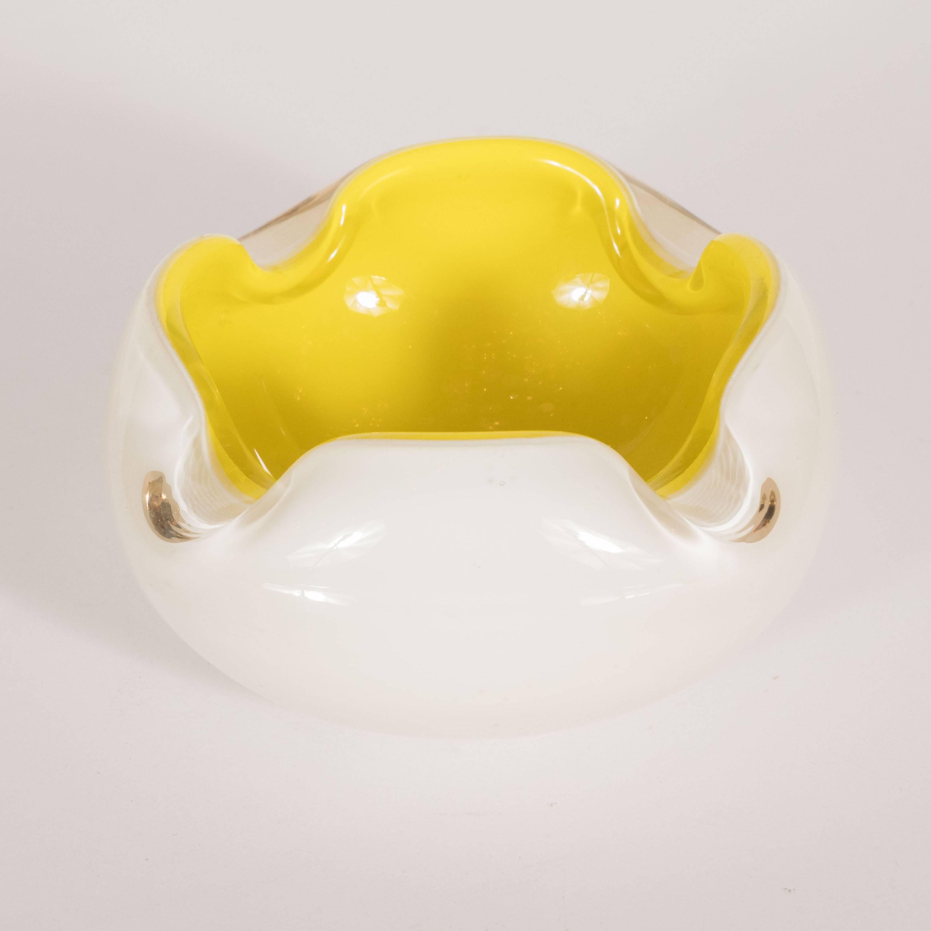 This stunning Mid-Century Modern dish features a white opaque skein and an ebullient lemon yellow interior with four depressions around the rim, imbuing the silhouette with dynamic sinuous curves. It would be perfect for presenting candies or nuts,