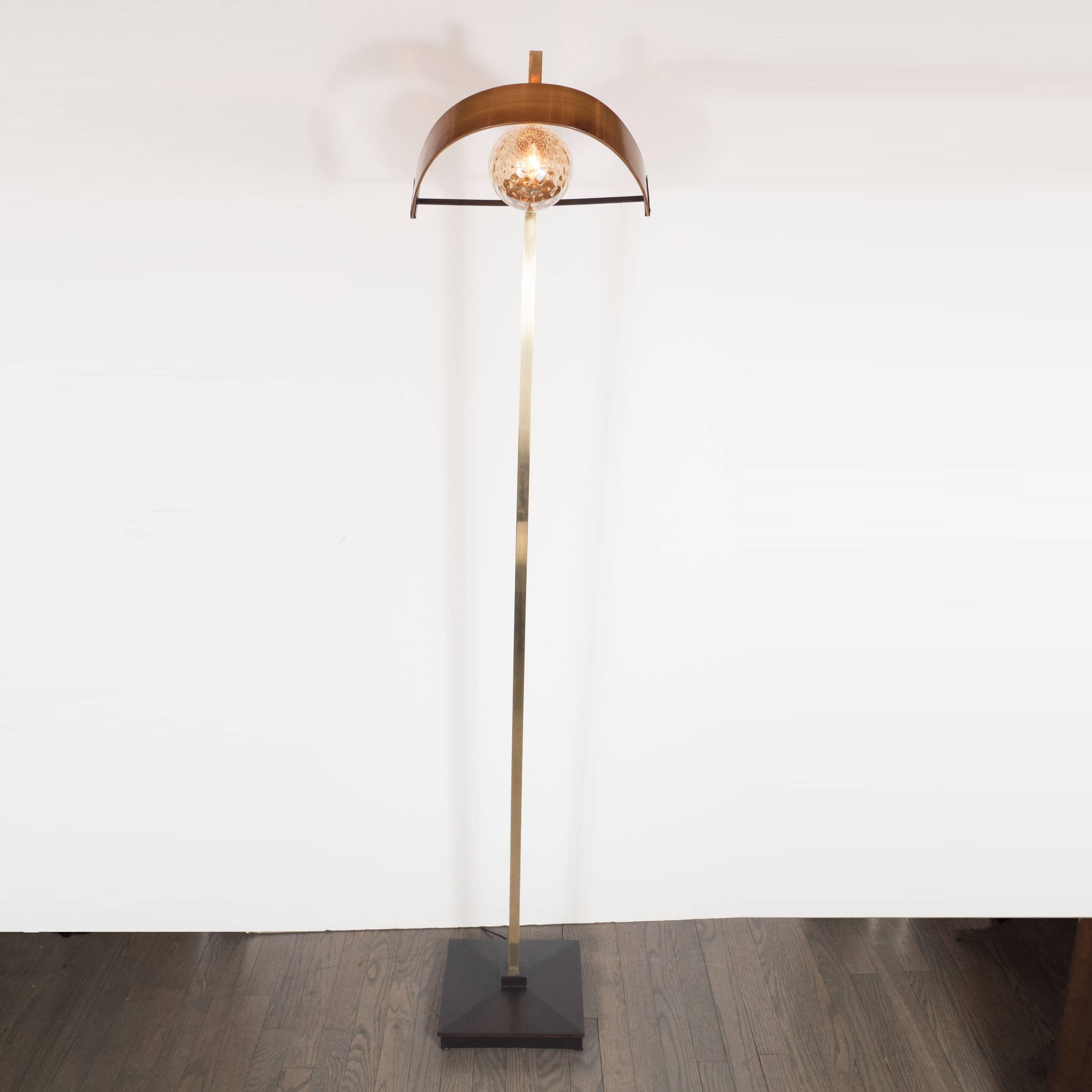 This sophisticated and sculptural floor lamp was realized in Italy, circa 1950. It is composed of an orbital shade in translucent textured glass shielded by an demilune form in hand rubbed walnut which attaches to a rectangular rod in polished