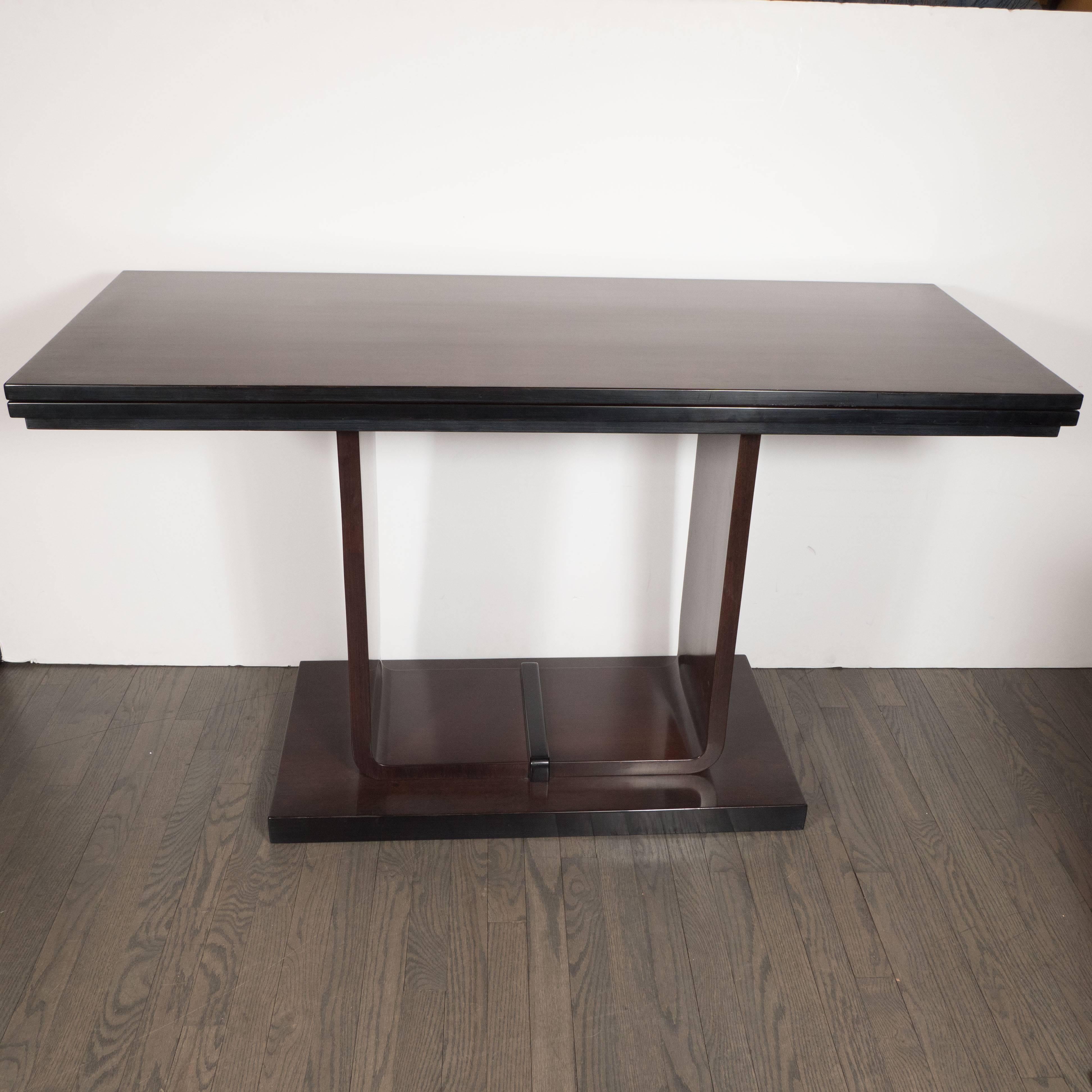 This refined Art Deco Skyscraper style Machine Age flip-top console or dining table was realized in the United States, circa 1935. Composed of book matched and burled Carpathian elm- that exhibits a particularly stunning woodgrain- this piece boasts
