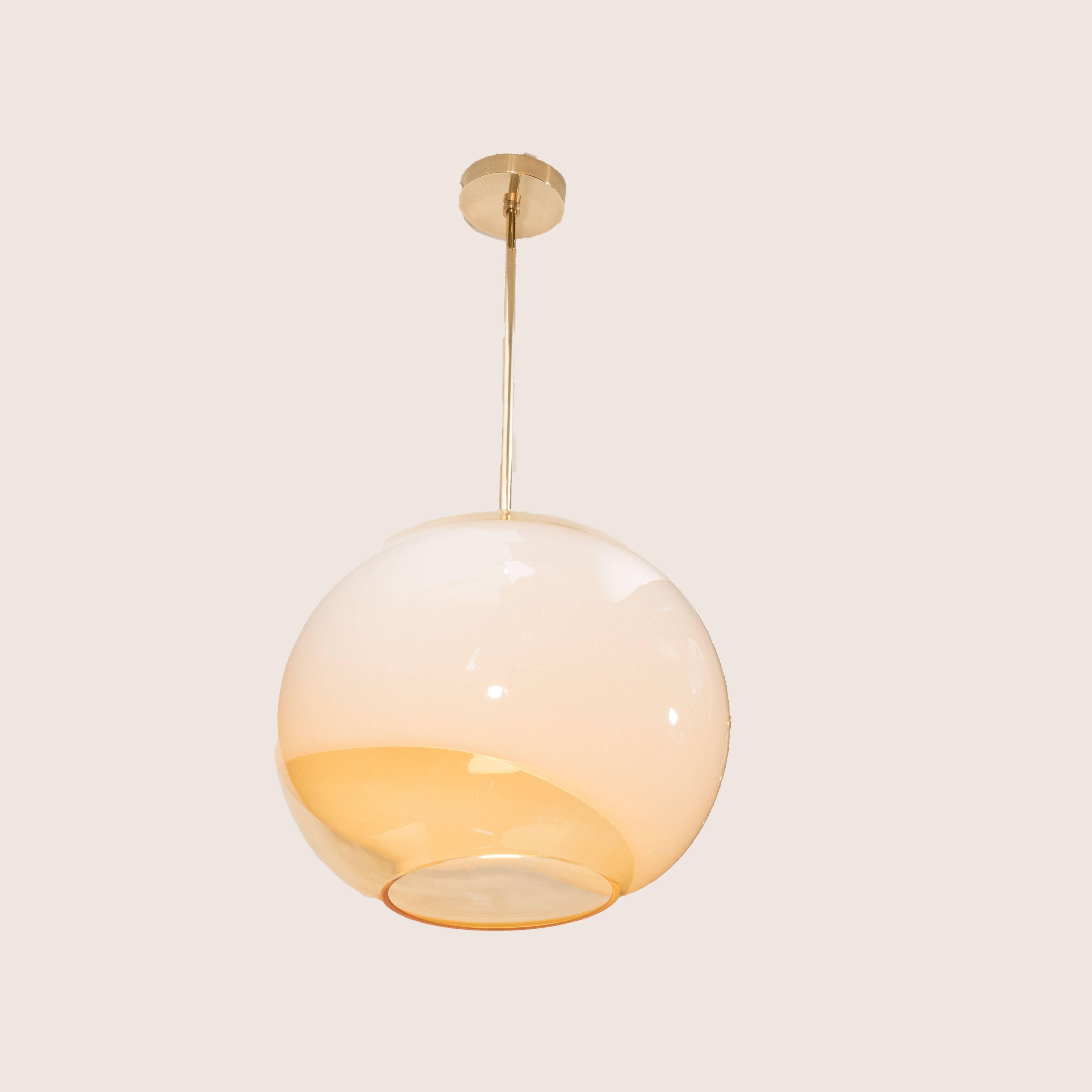 This refined pendant was realized in Italy, circa 1970. It offers an orbital form with a circular aperture at its bottom and a concave opening at top. Composed of translucent glass in a subtle amber hue, it is infused with a sinuous band in opaque