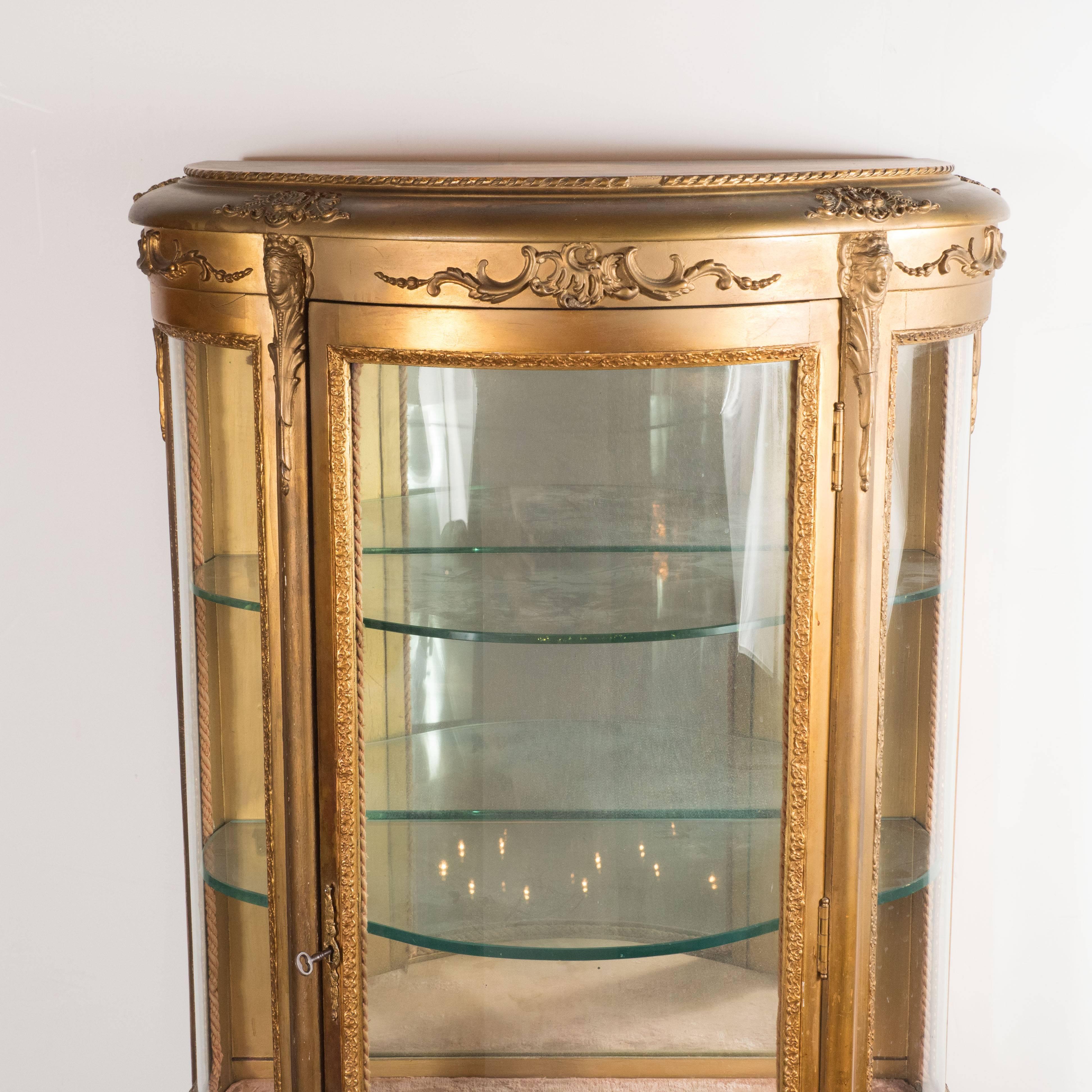 This exquisite display case was realized by the esteemed French maker Vernis Martin in the mid-19th century. Created in the manner of Louis XVI, it features an ormolu body with an abundance of baroque details. Consisting of a demilune form, the top