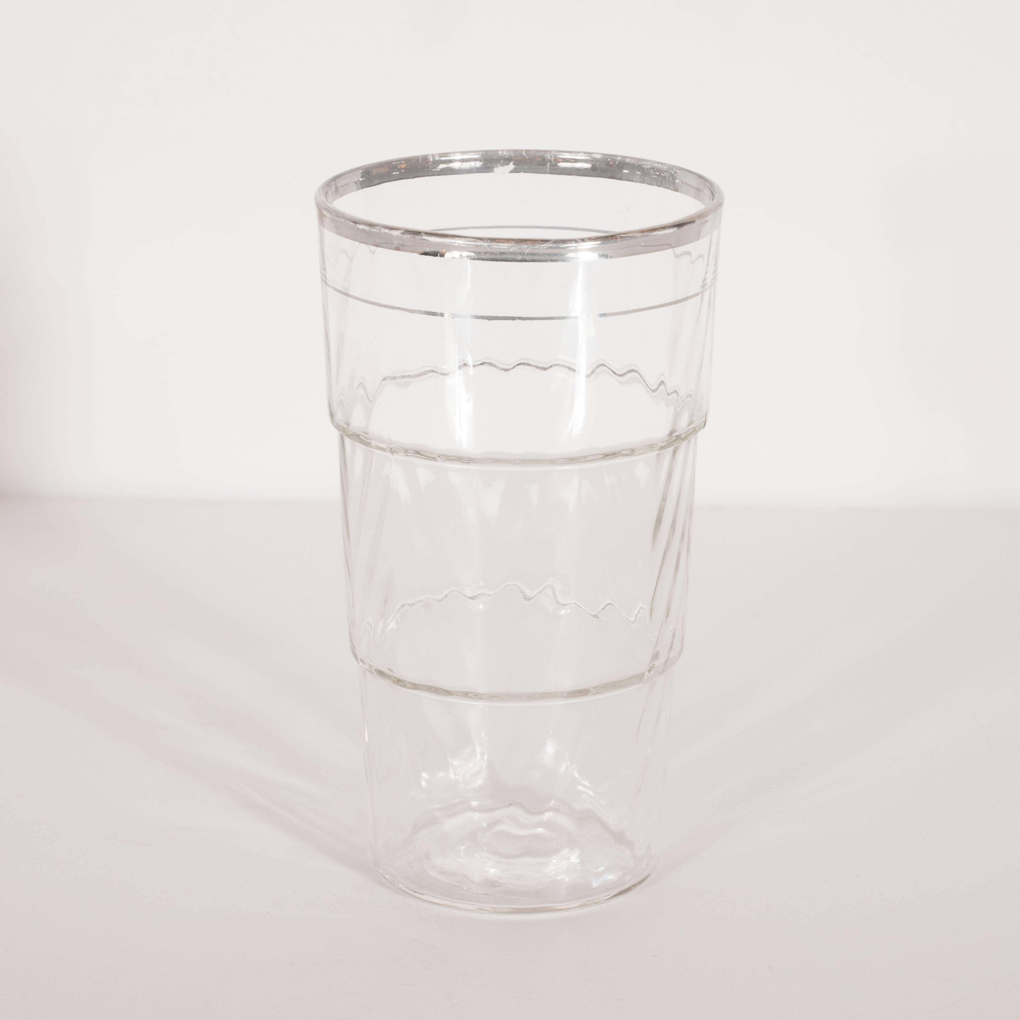 This elegant set of four glasses were realized in the United States, circa 1935. They offer a skyscraper style design composed of three tiers of ascending diameter in textured glass with subtle raised angular ridges that suggest a chevron pattern.