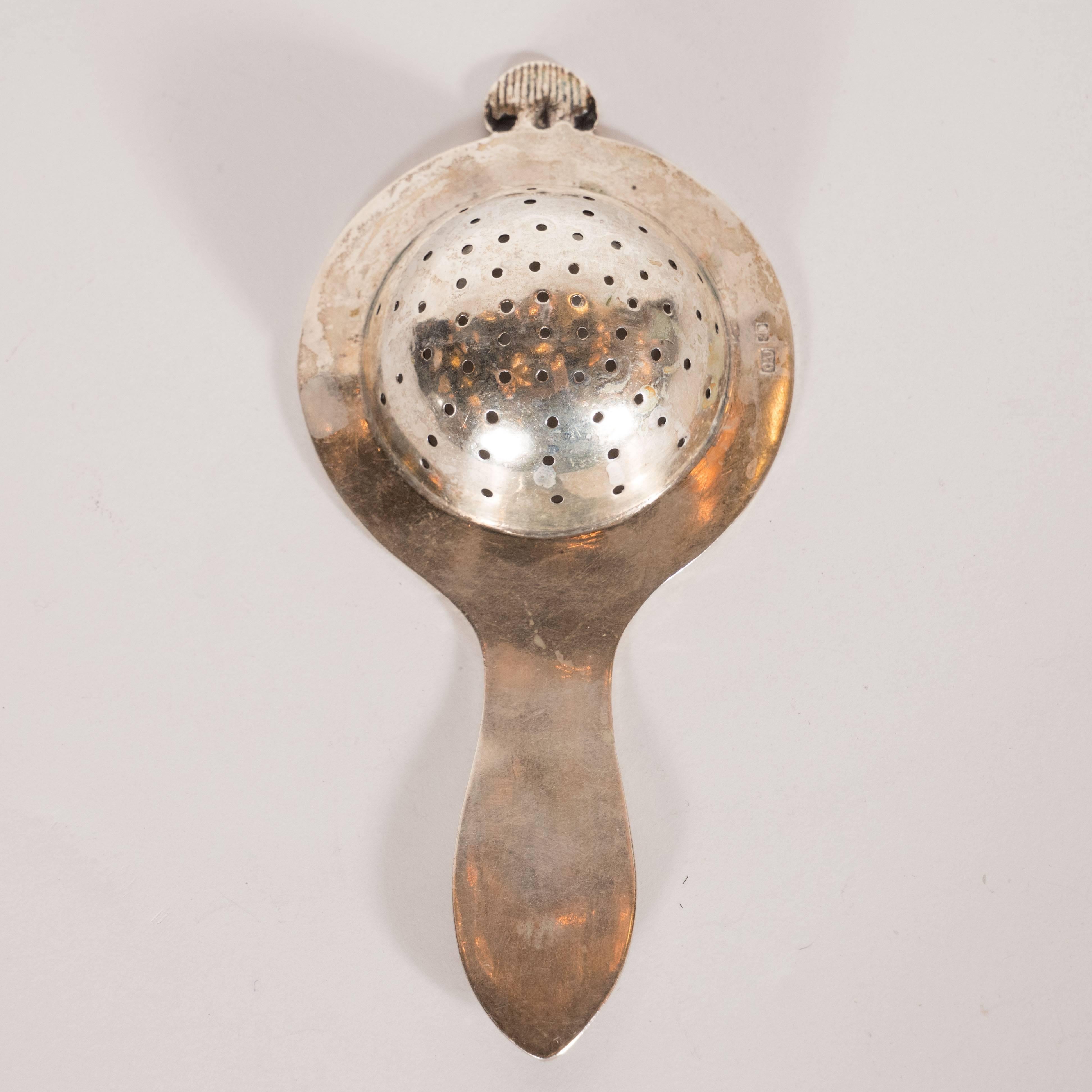 This beautiful and refined tea strainer was realized in England- arguably the birthplace of fine silverware- during the 19th century. It features a concave and perforated depression, perfect for steeping tea; a striated cupola form at top; a subtle