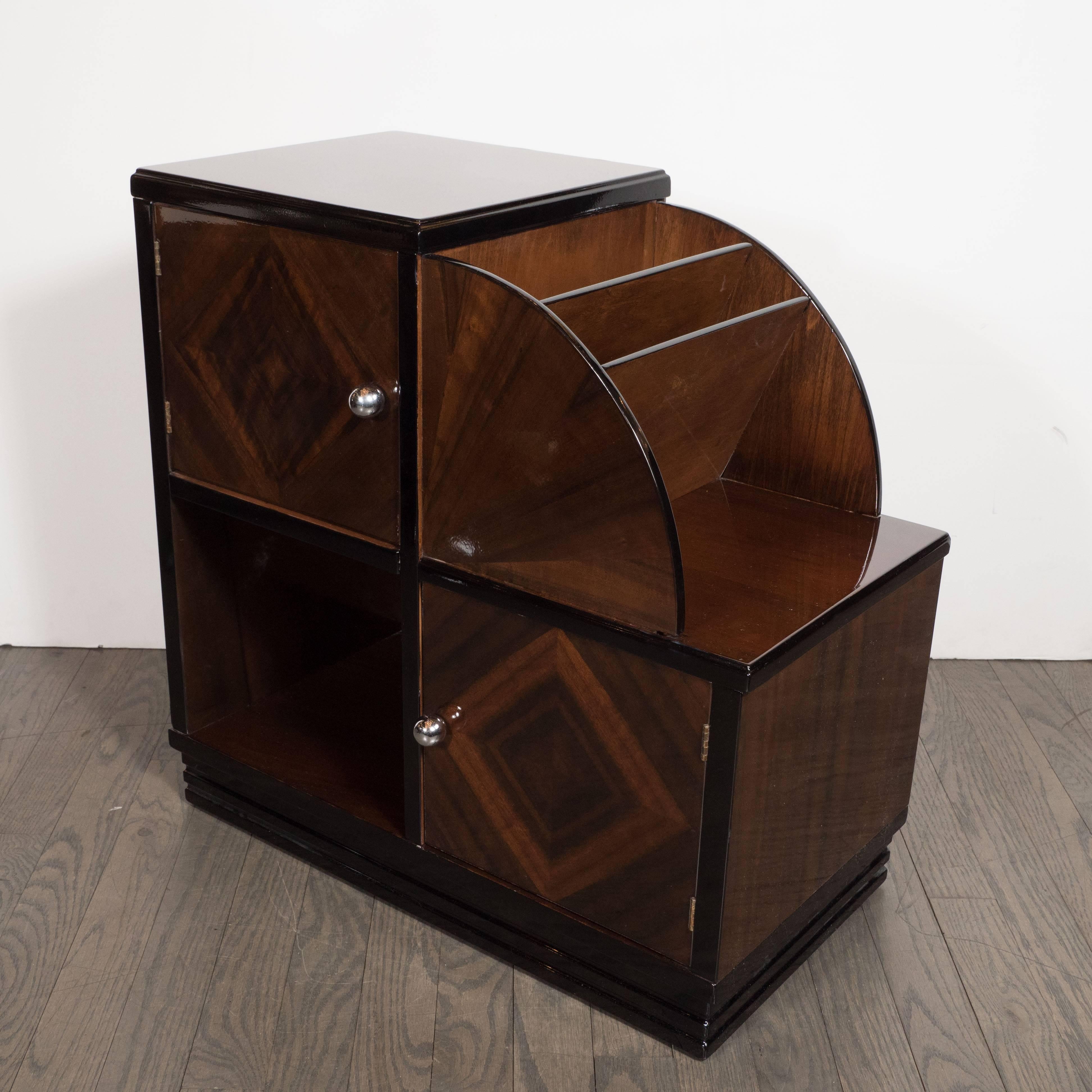 This stunning magazine stand was realized in the United States, circa 1935. It offers two cabinets with chrome pulls arranged caddy corner connected a square cut-out compartment on bottom and a demilune form on top with two shelves. There are two