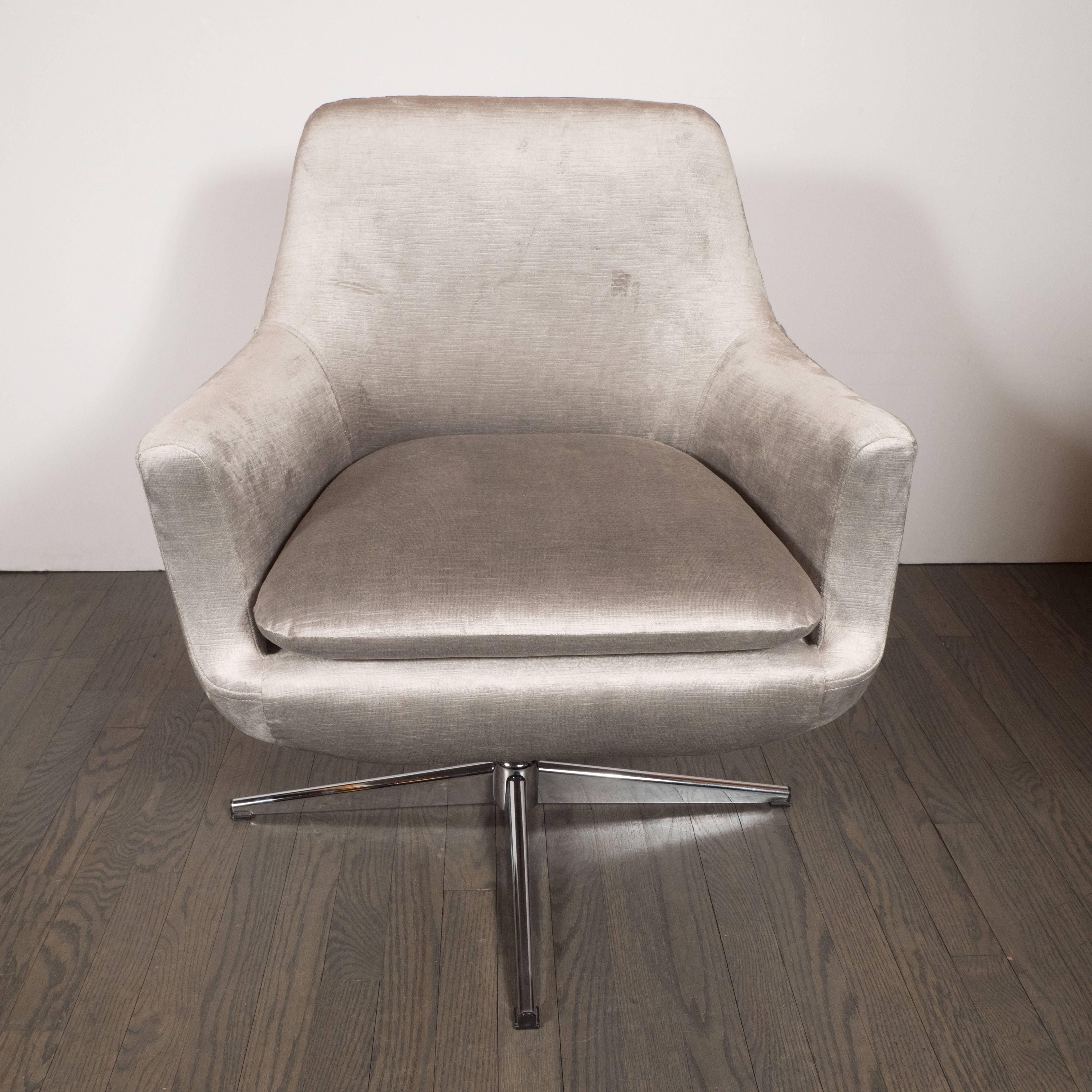 This refined pair of Mid-Century Modern sculptural swivel chairs were realized in the United States, circa 1970. They feature an X-form base in polished chrome; sloping arms; a rectangular back with rounded corners; and a detachable seat cushion.