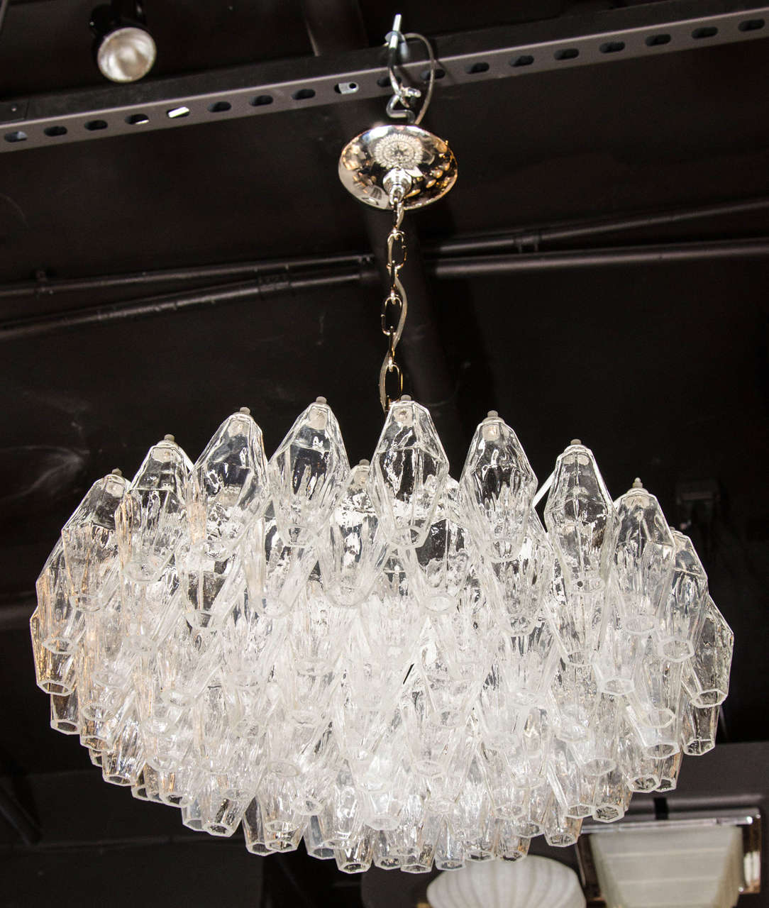 This luminous modernist glass chandelier features numerous handblown Murano translucent glass polyhedral shades. Each glass polyhedral shade is individually hung from its frame by hand. The frame features the subtle upward graduation from its center