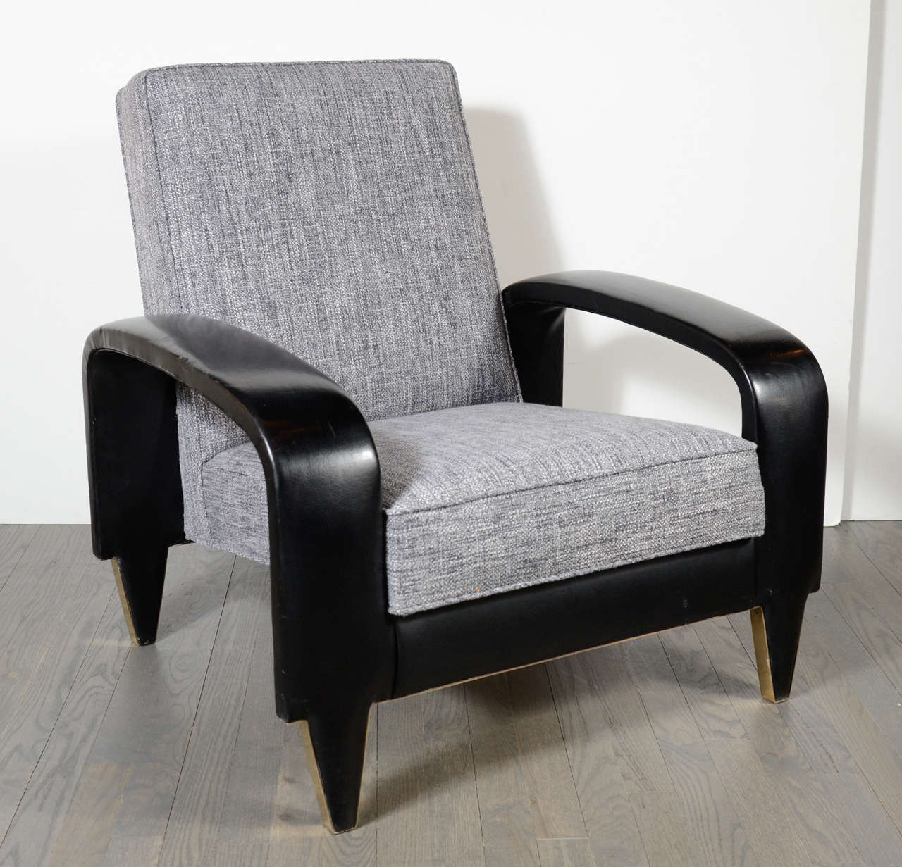 This rare Art Deco club chair features sculptural banded upholstered leather arms and new woven grey and pearl tweed upholstery. It has tapered legs with brush brass details and came from an Italian cruise liner.
