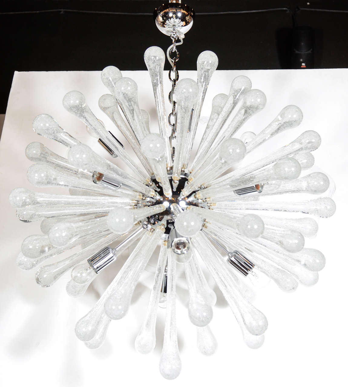 This gorgeous glass Sputnik chandelier was realized in Murano, Italy- the island off the coast of Venice renowned for centuries for its superlative glass production. It features an abundance of translucent hand blown Murano textured glass rods with