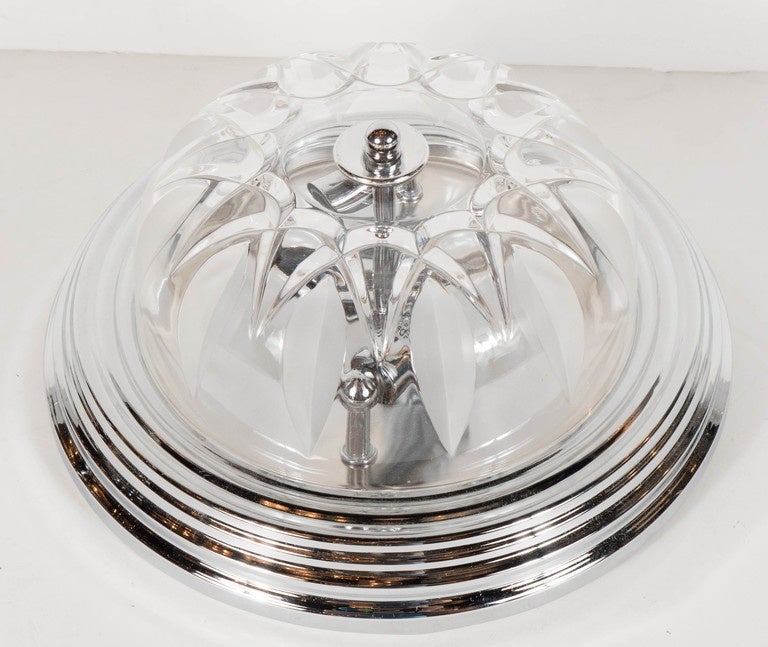 Art Deco style flush mount chandelier with chrome fittings. This Art Deco style flush mount chandelier features a rounded chrome canopy with a multi-tiered stepped Skyscraper style designed outer trim that holds its hand-cut crystal dome that