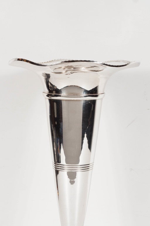 This elegant pair of Art Deco silver plate trumpets feature a tulip opening with etched rim detailing tapering down to a round base. At the mid-point of each vase is a fine lineal concentric ribbed detail. They are in excellent condition.