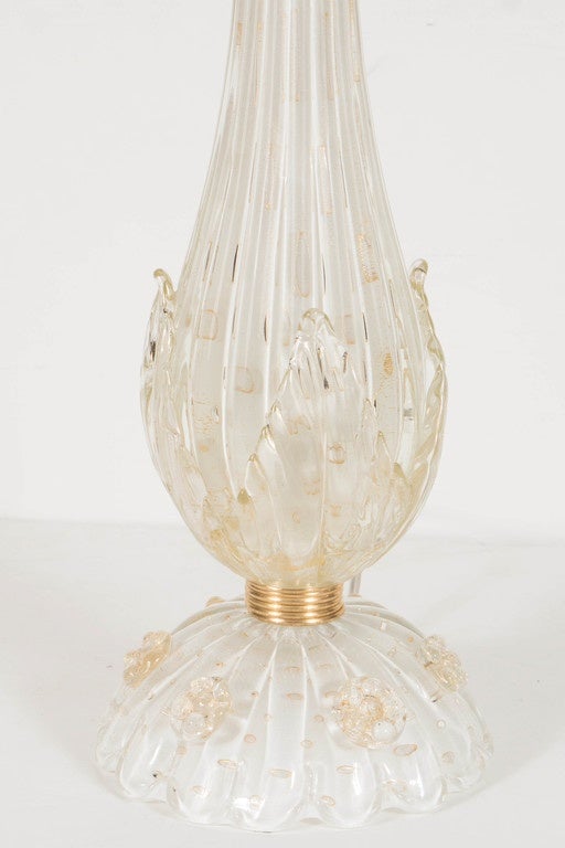 This gorgeous pair of Murano glass lamps by Barovier & Toso feature a teardrop form with stylized leaves on a rounded base with floret detailing separated by a ribbed polished brass band. This lamp has fluting throughout and 24-karat gold flecks.