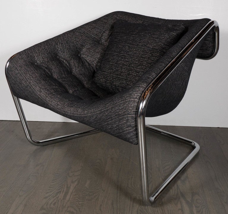 Mid-Century Modernist tubular angled cantilever lounge chair with a chrome frame and upholstered in a tufted metallic platinum and black tweed upholstery. This lounge chair features a wide sloped seat with raised sides and sloped back. The excess of